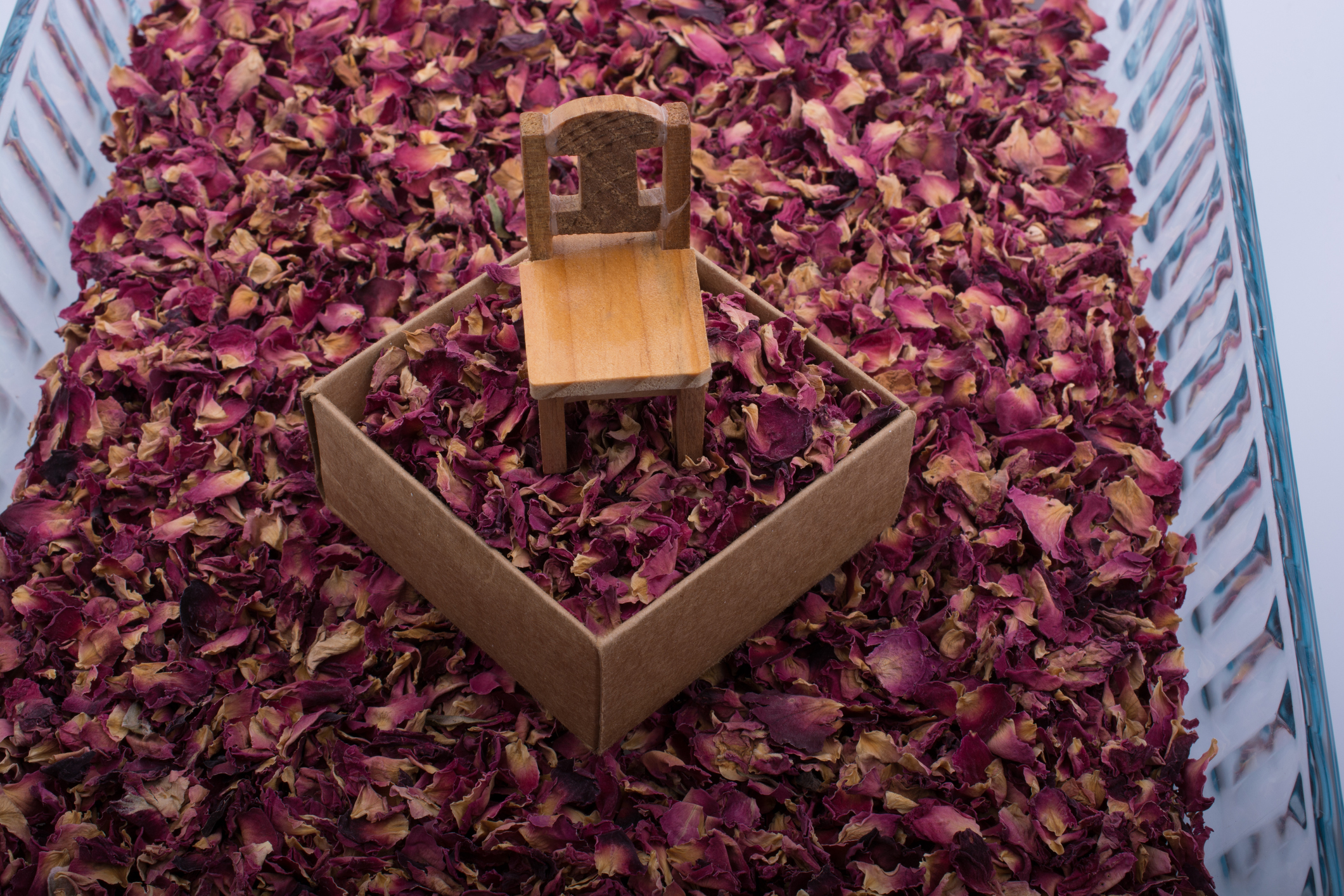 Toy chair on a box filled with petals