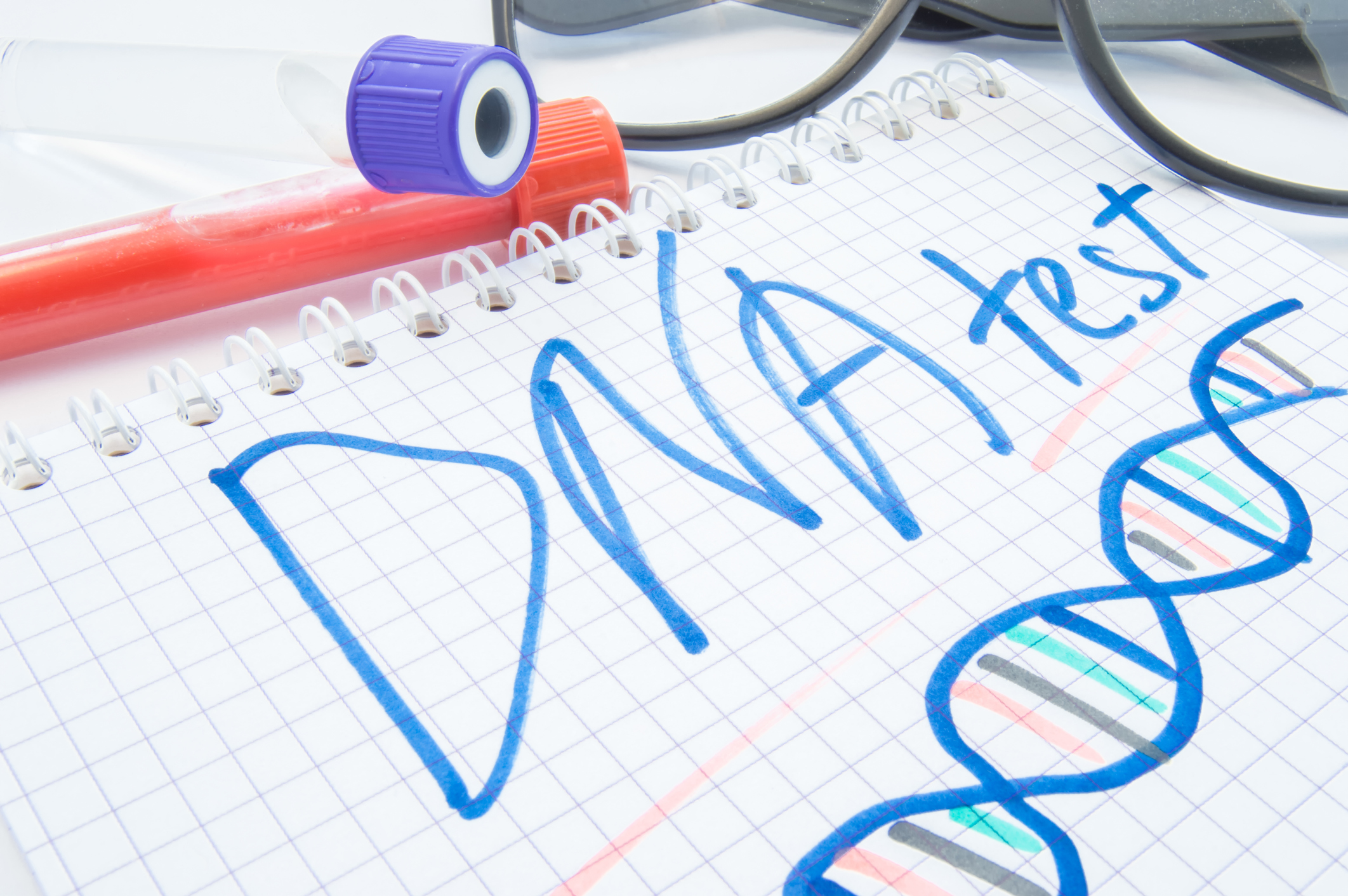 Note labeled DNA test and DNA formula lies next to test tubes with blood, biomaterial and glasses. DNA test or analysis procedure concept to determine ancestry, paternity, familytree, genetic diseases