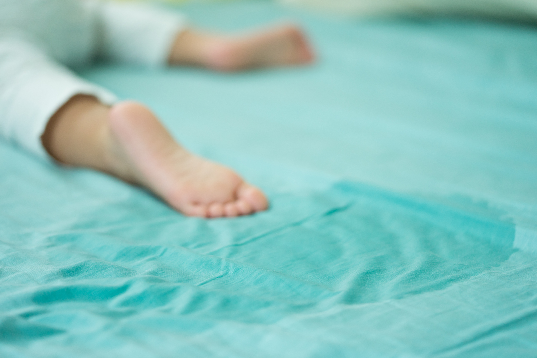 Kid's feet and pee in a mattress.Little girl feet and pee in bed sheet on the morning.Child development concept.