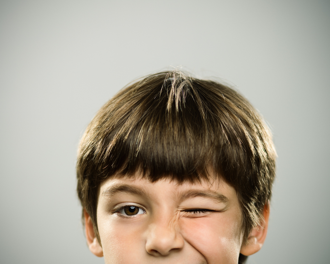 Portrait of a caucasian real boy winking.