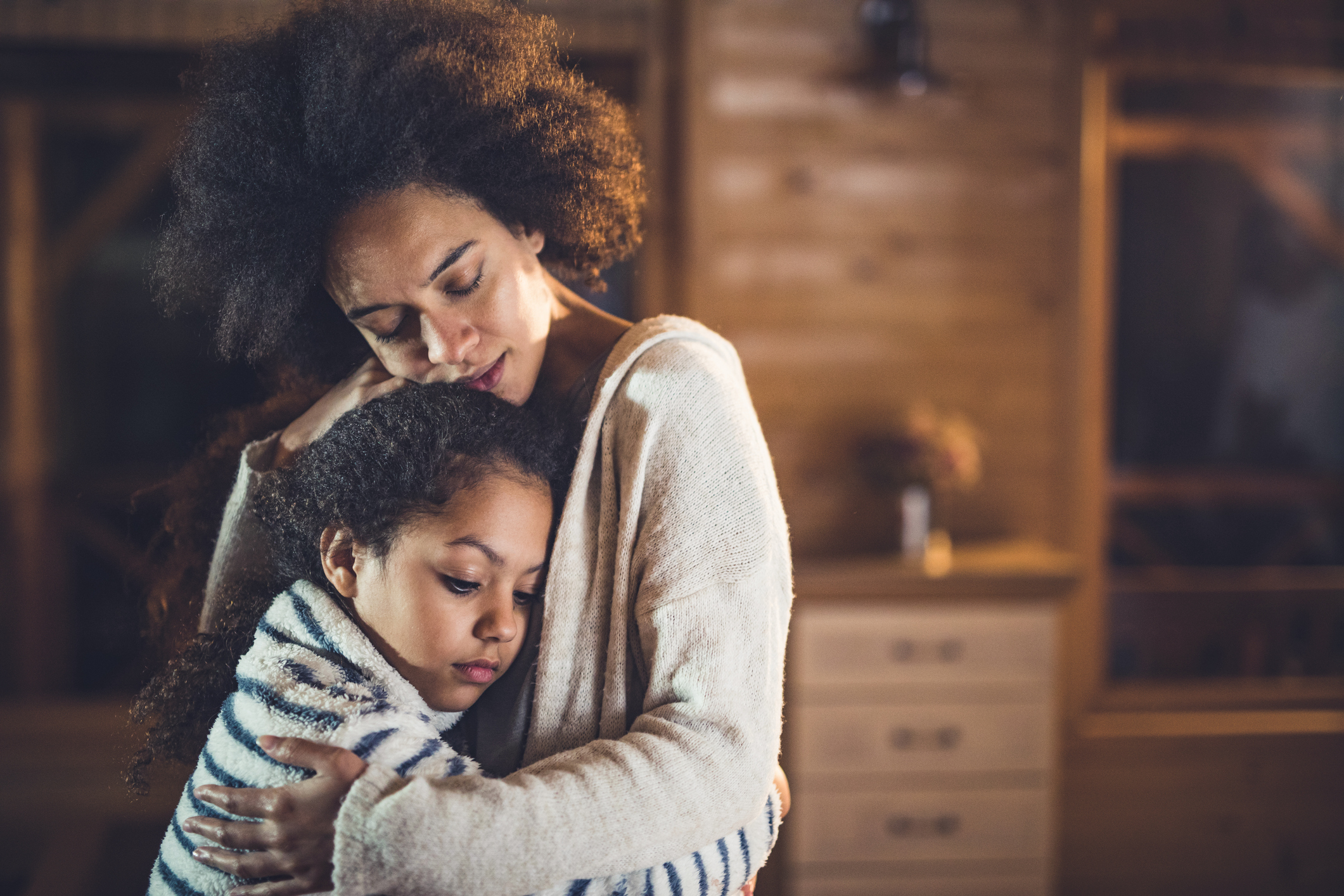 African American mother and daughter embracing at home.