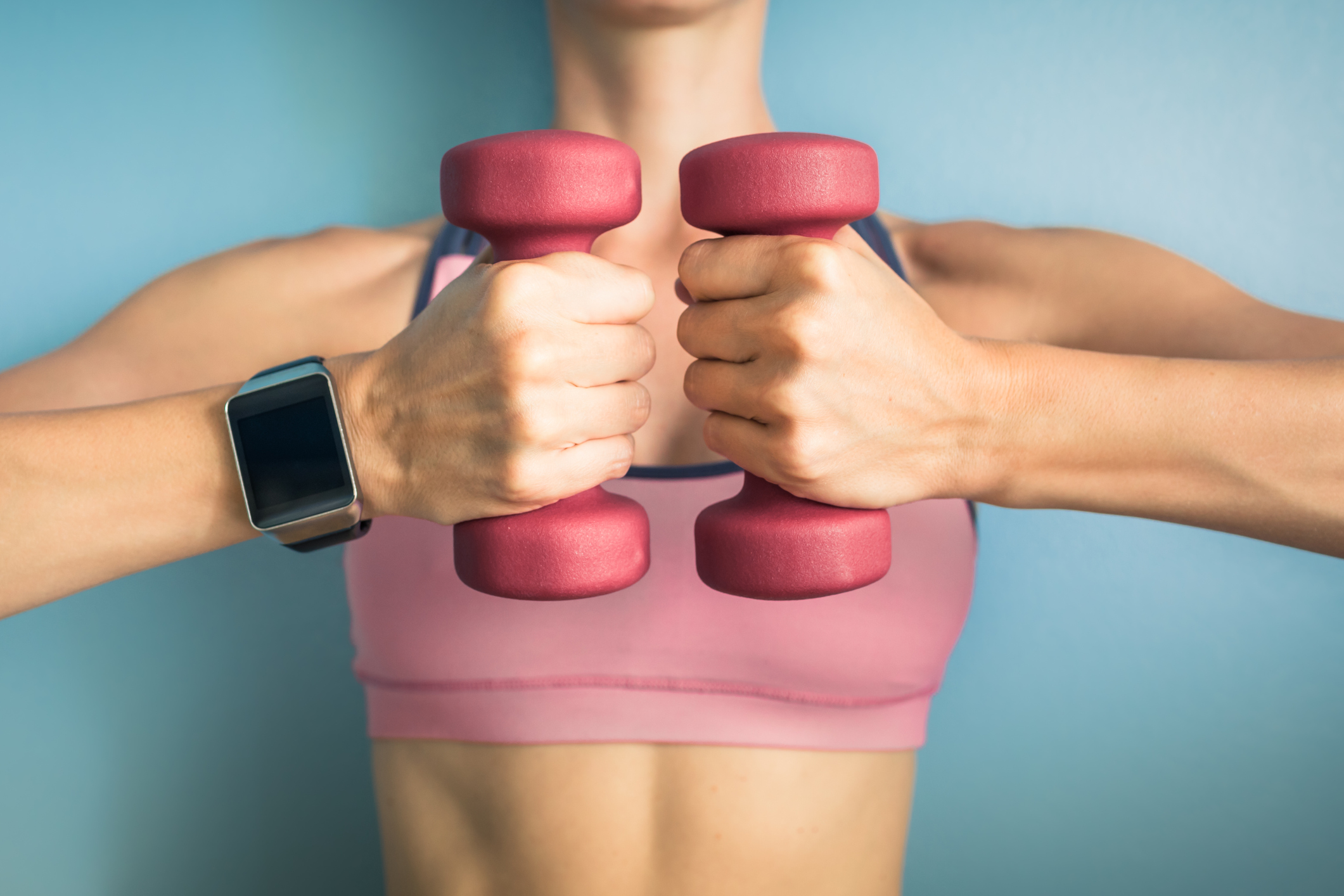 Fit girl holding weights and wearing smartwatch.