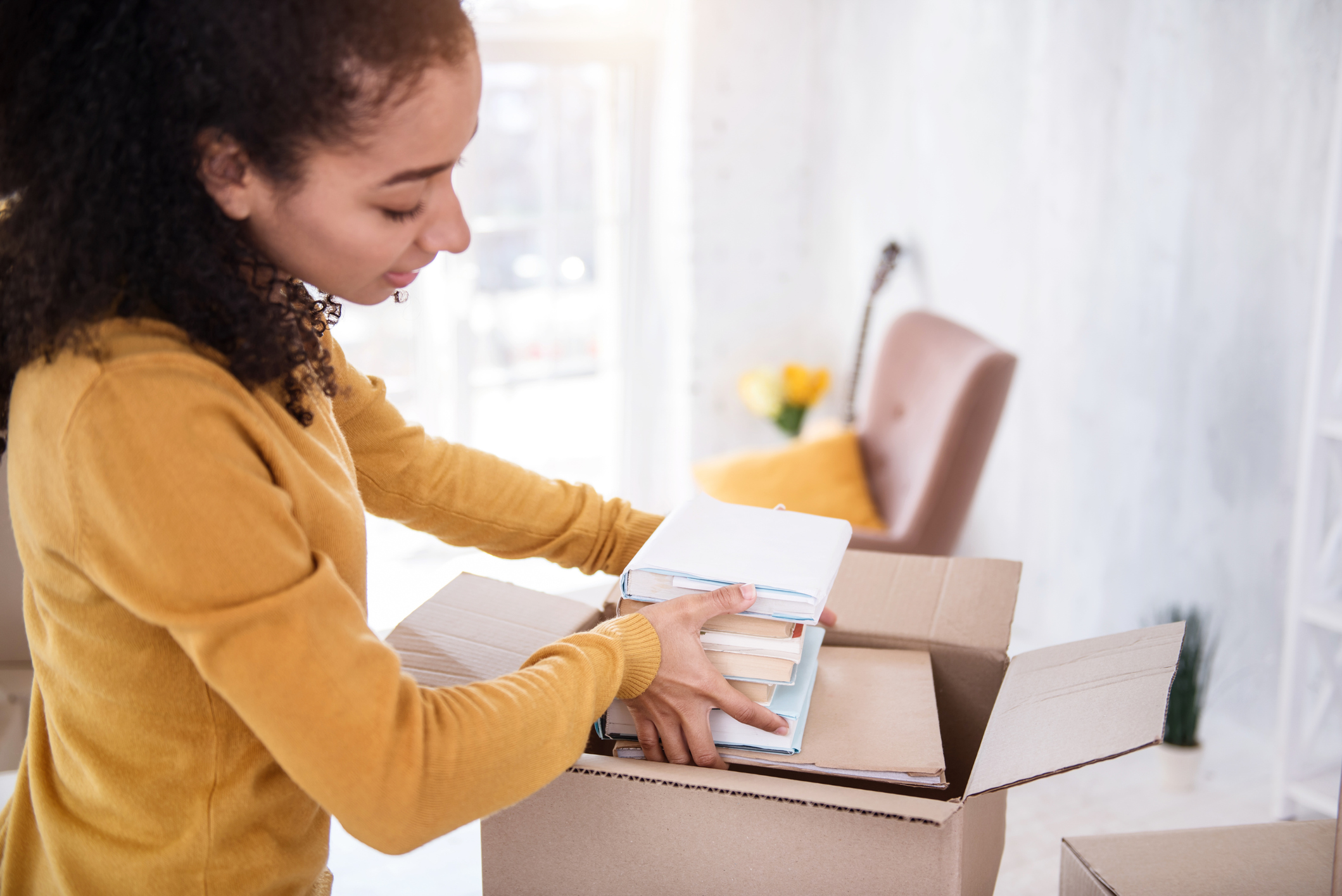 Pretty curly girl fitting books into the box