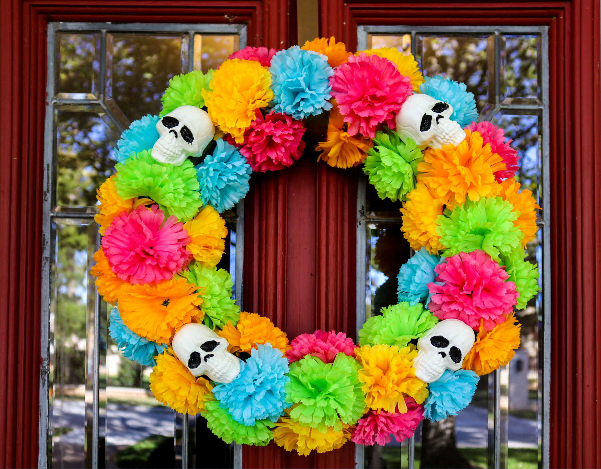 Day of the Dead wreath on door with tree and neighborhood reflected in beveled glass window