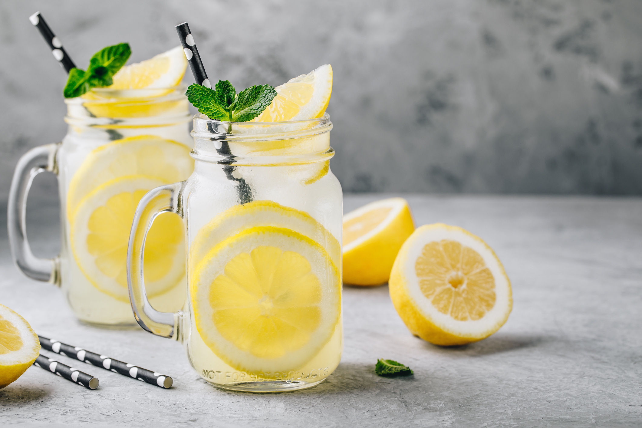 Homemade refreshing summer lemonade drink with lemon slices and ice in mason jars