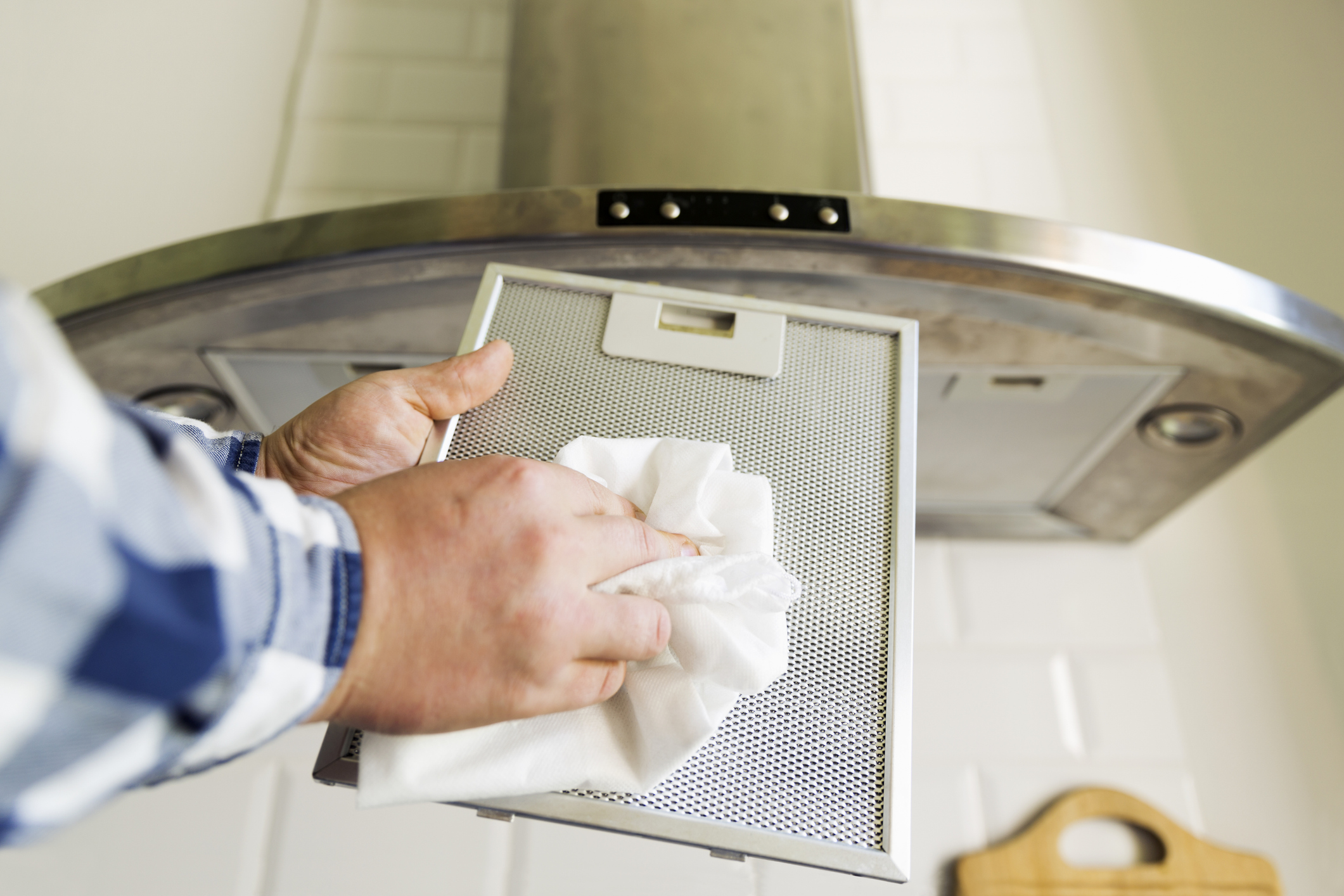 Man's hands cleaning aluminum mesh filter for cooker hood. Housework and chores. Kitchen cooker hood on the background