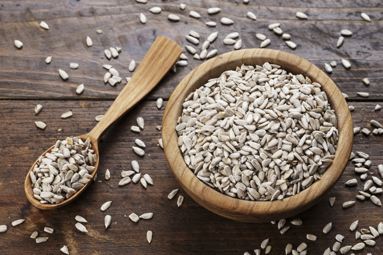 Peeled sunflower seeds on a wooden background in a plate.