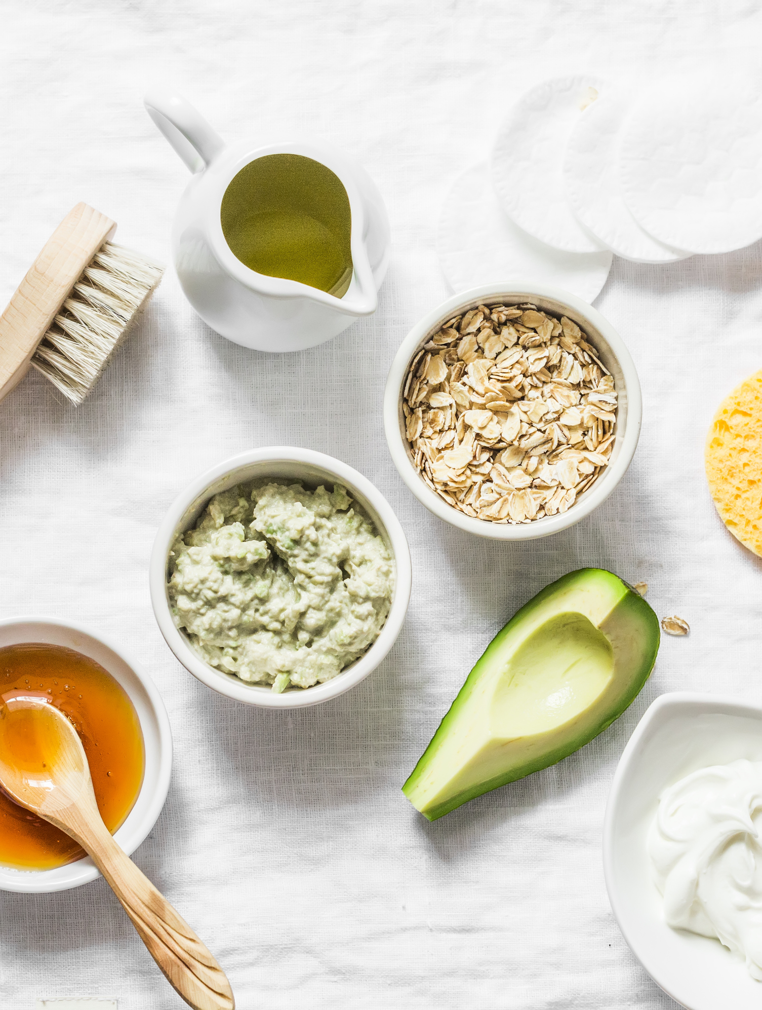 Ingredients for moisturizing, nourishing, anti-aging wrinkle face mask - avocado, olive oil, oatmeal, natural yogurt on light background, top view. Homemade beauty products concept