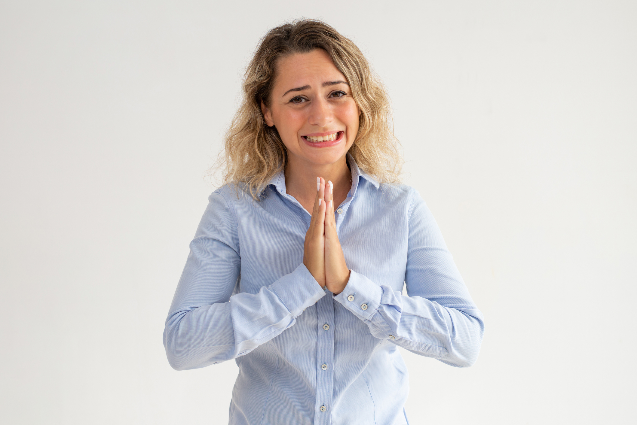 Scared young woman holding hands together and begging