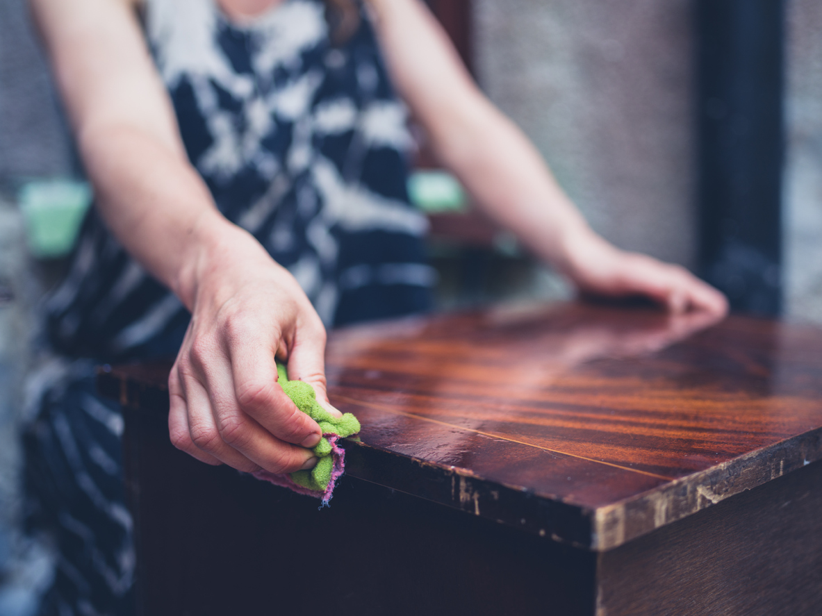 Young woman cleaning old furniture