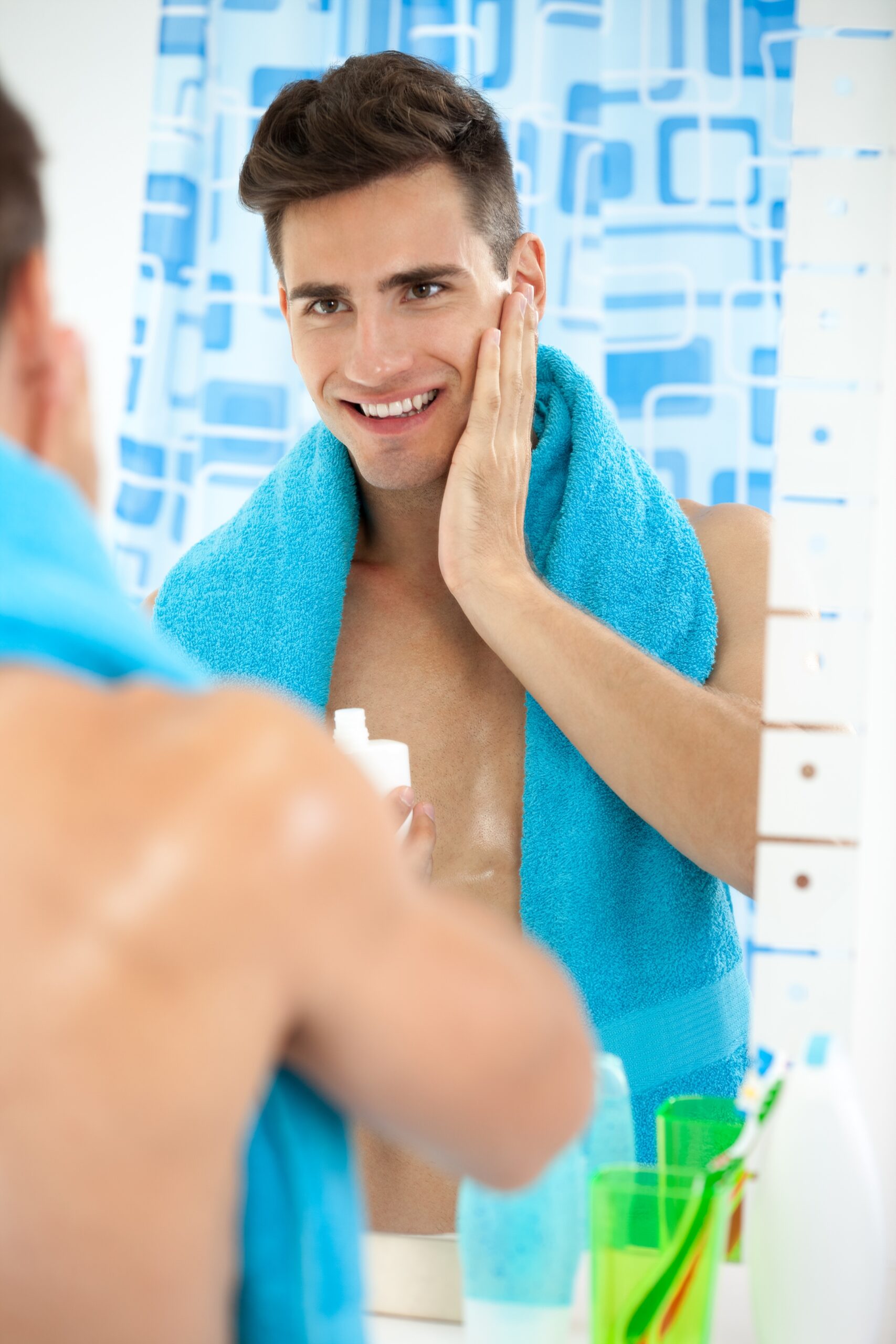 Young handsome man applying aftershave, skincare