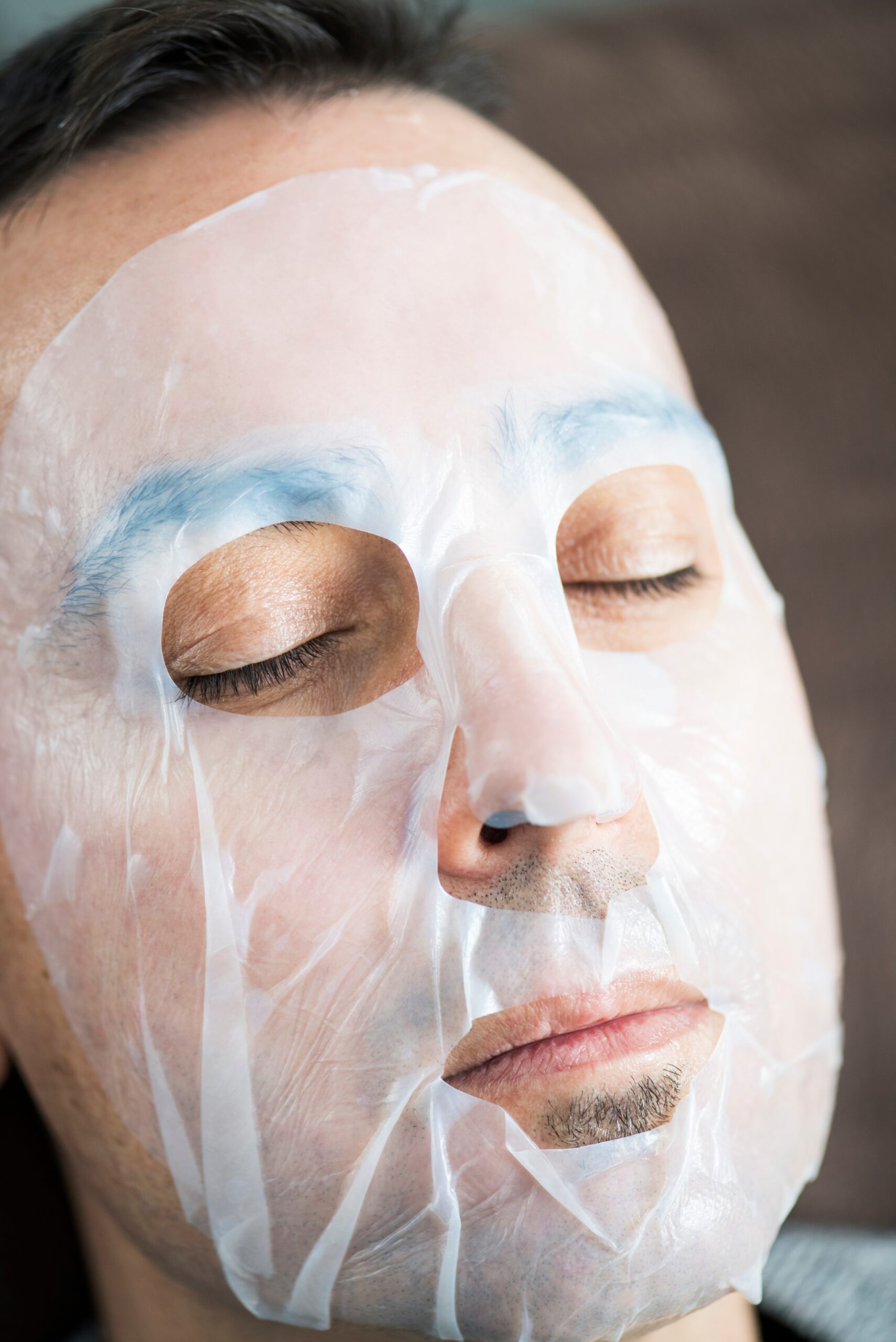 closeup of a handsome caucasian man wearing a bio-cellulose sheet mask