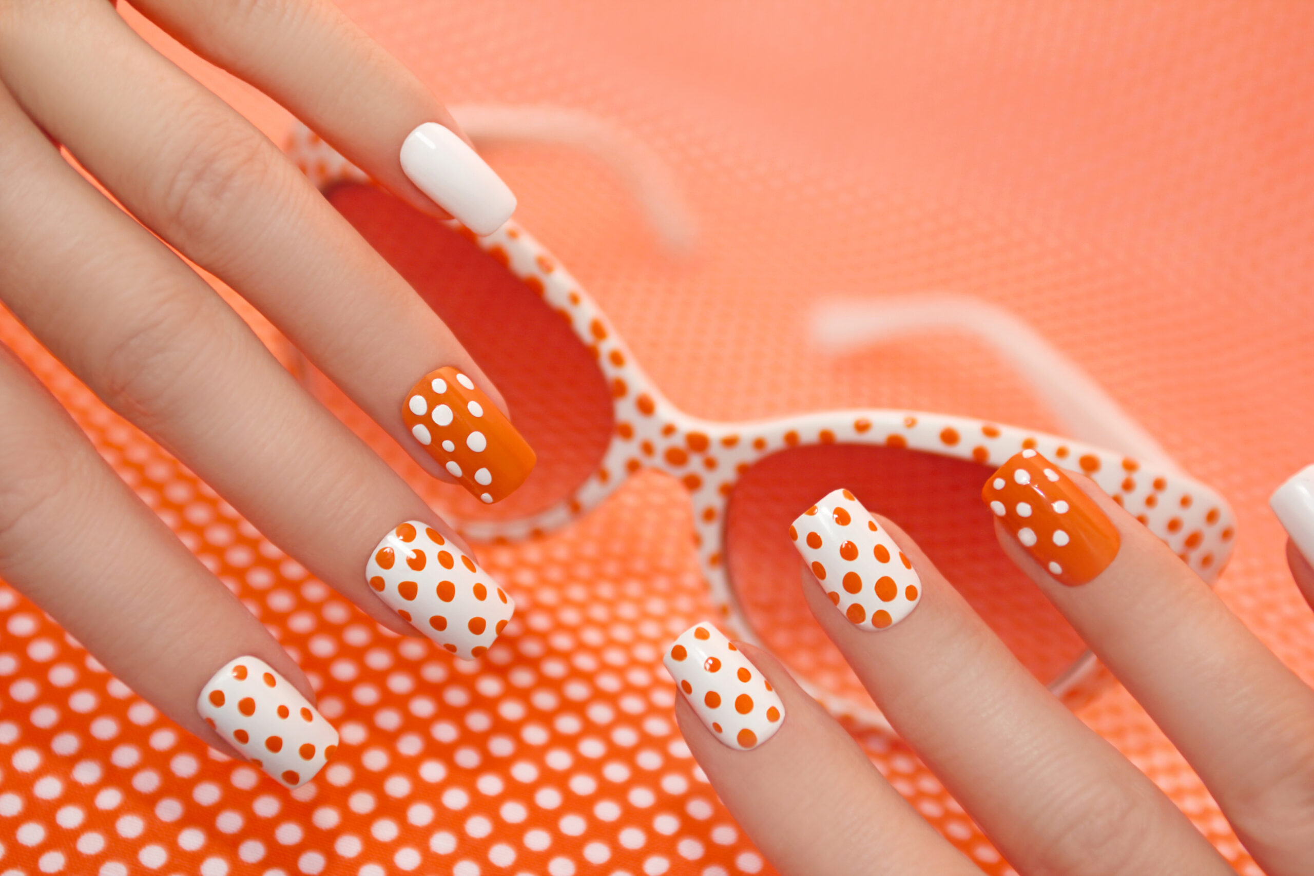 Sunny orange manicure with dots .