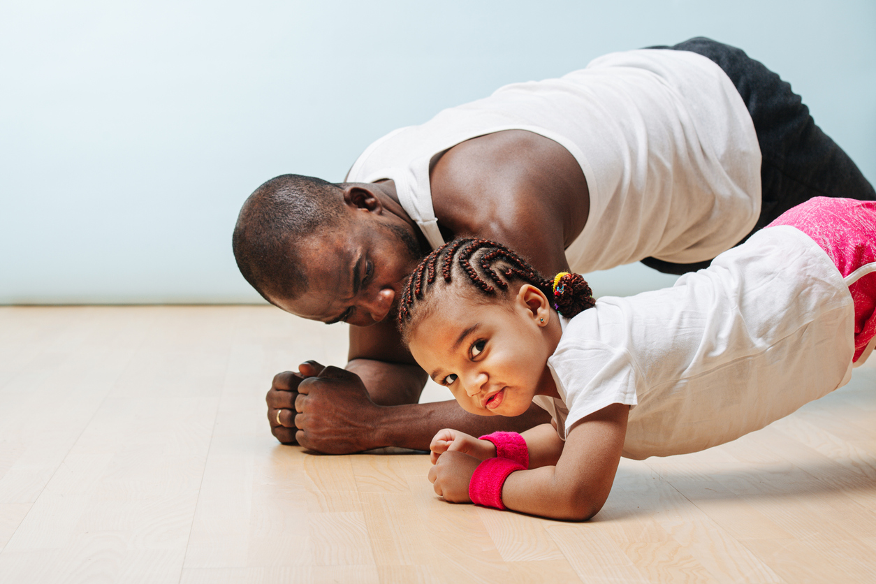 Father and daughter staying in shape in isolation, doing plank