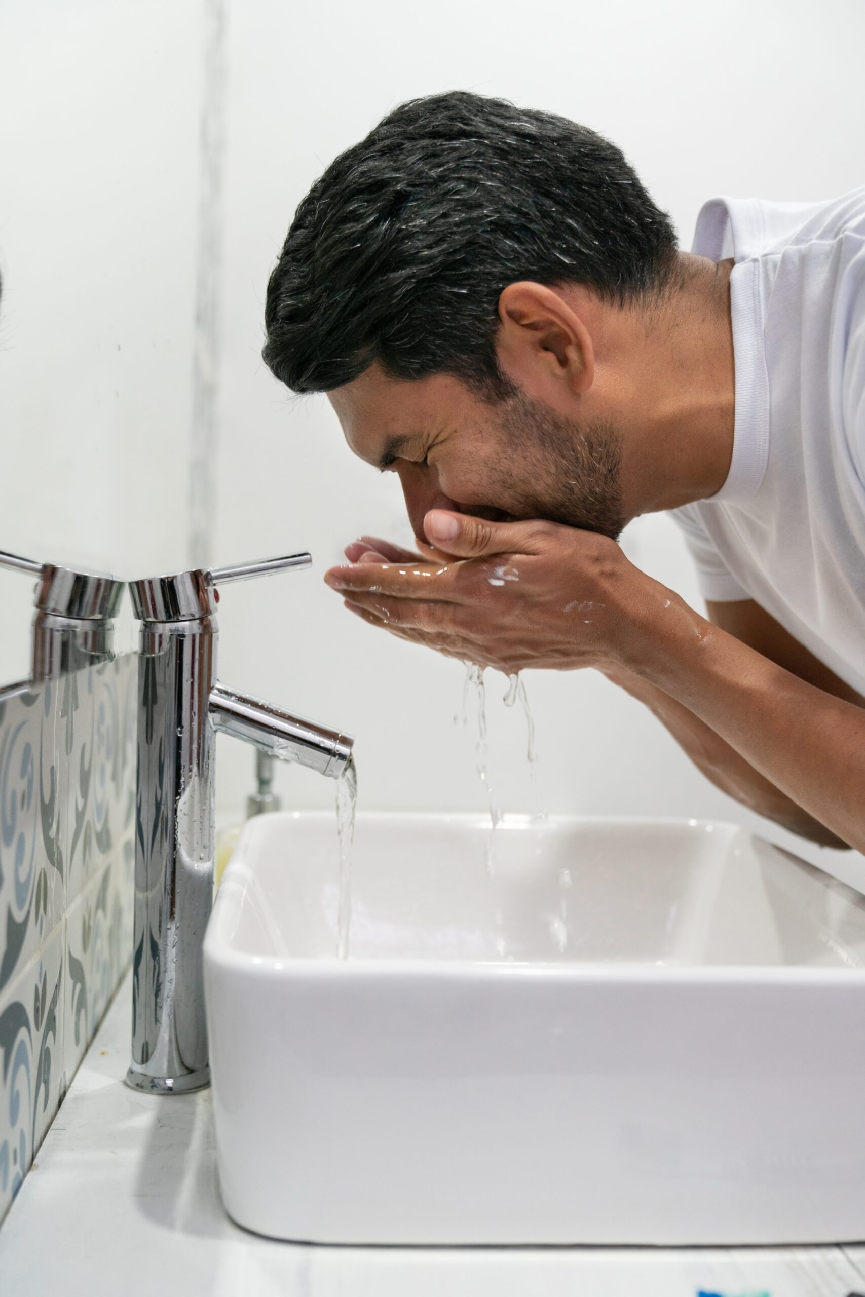 Latin american man washing off shaving cream  - Morning routine