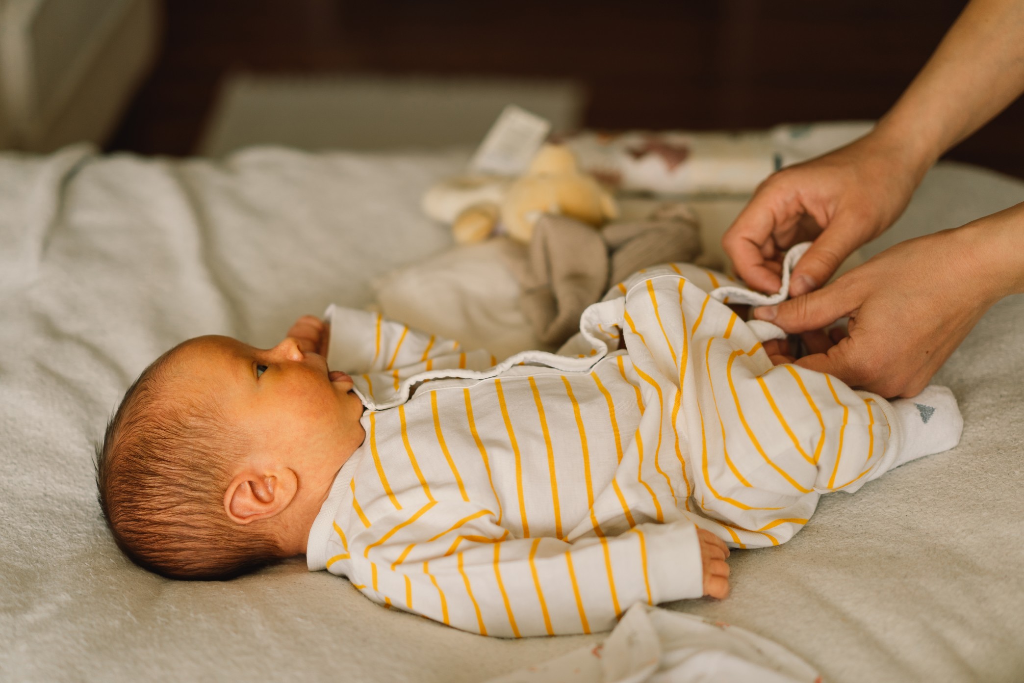 mom-dresses-cute-newborn-little-baby-boy-in-a-jumpsuit-happy-young-mother-playing-with-baby-while_t20_xGajXB-1.jpg