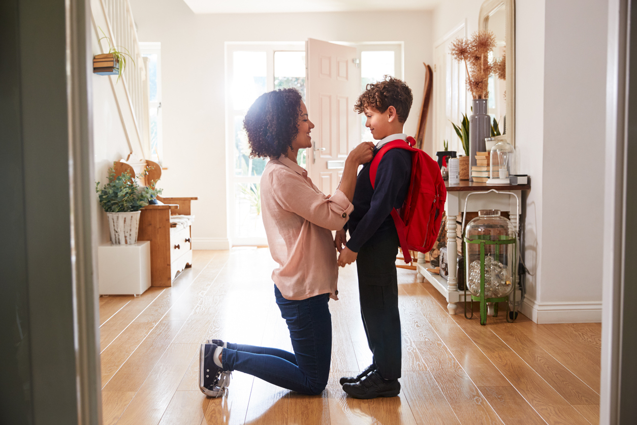 Single Mother At Home Getting Son Wearing Uniform Ready For First Day Of School