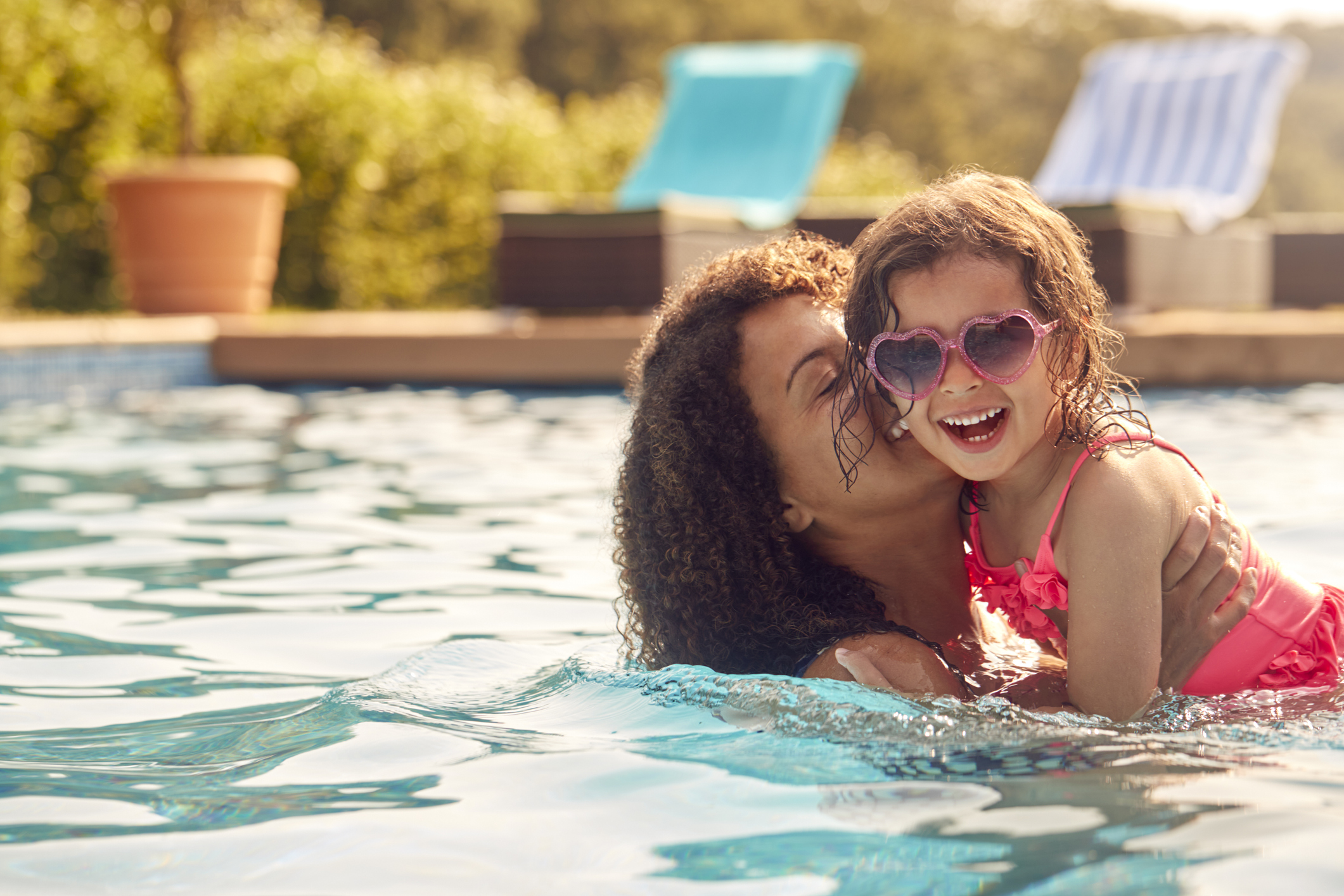 Laughing Mother And Daughter Wearing Sunglasses Having Fun In Swimming Pool On Summer Vacation