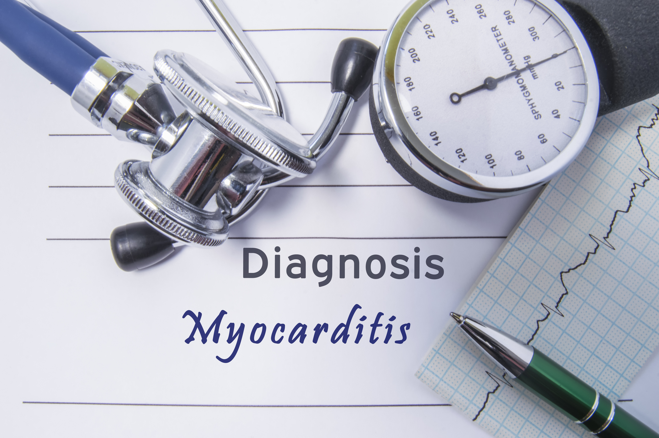 Cardiac diagnosis Myocarditis. Medical form report with written diagnosis of Myocarditis lying on table in doctor cabinet, surrounded by stethoscope, sphygmomanometer and ecg. Concept for cardiology