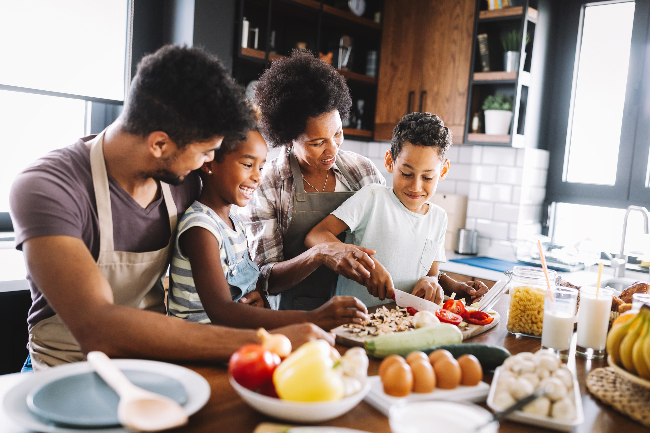 Happy african american family preparing healthy food together in kitchen