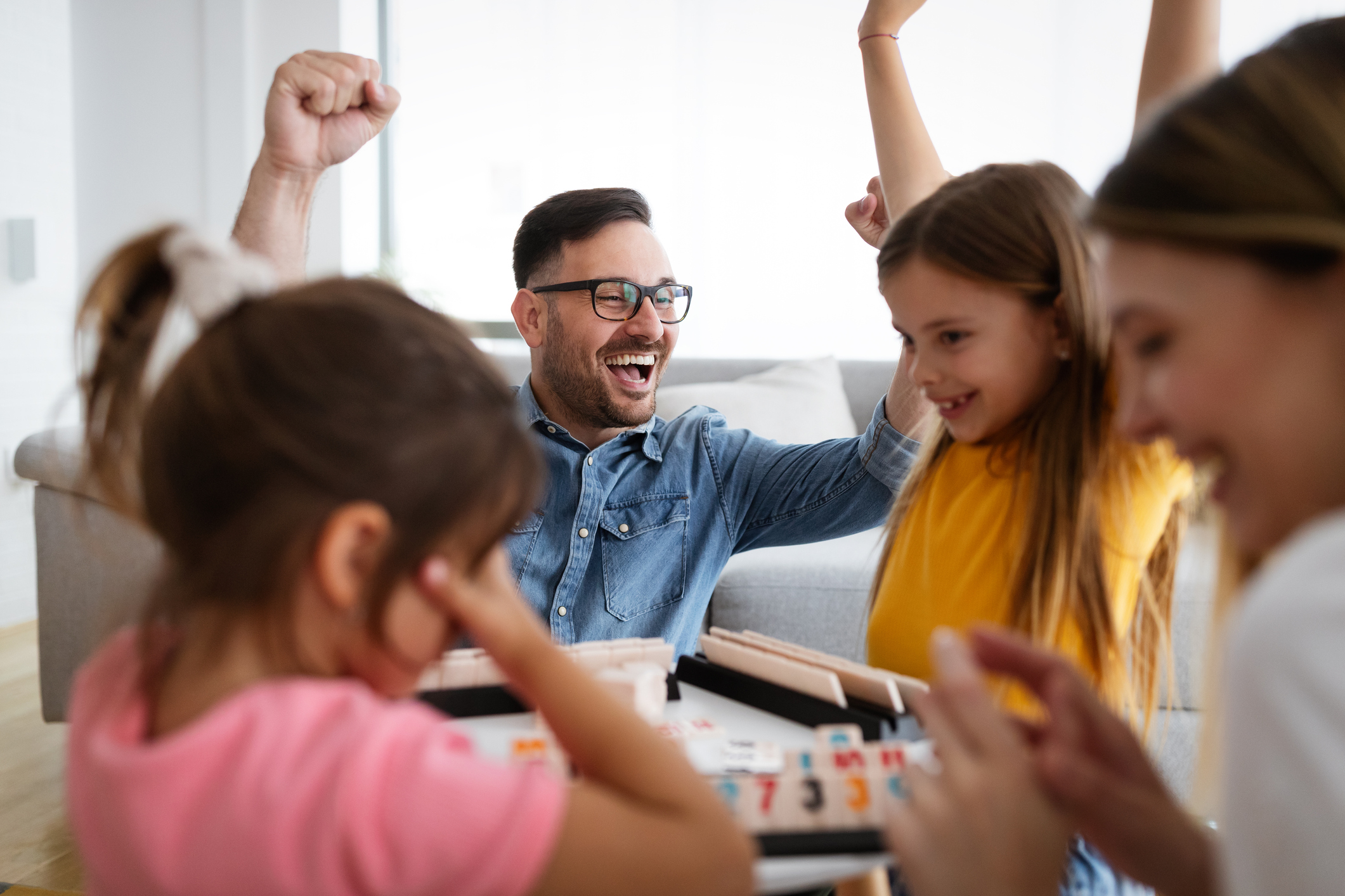 Happy young parents and children having fun, playing board game at home