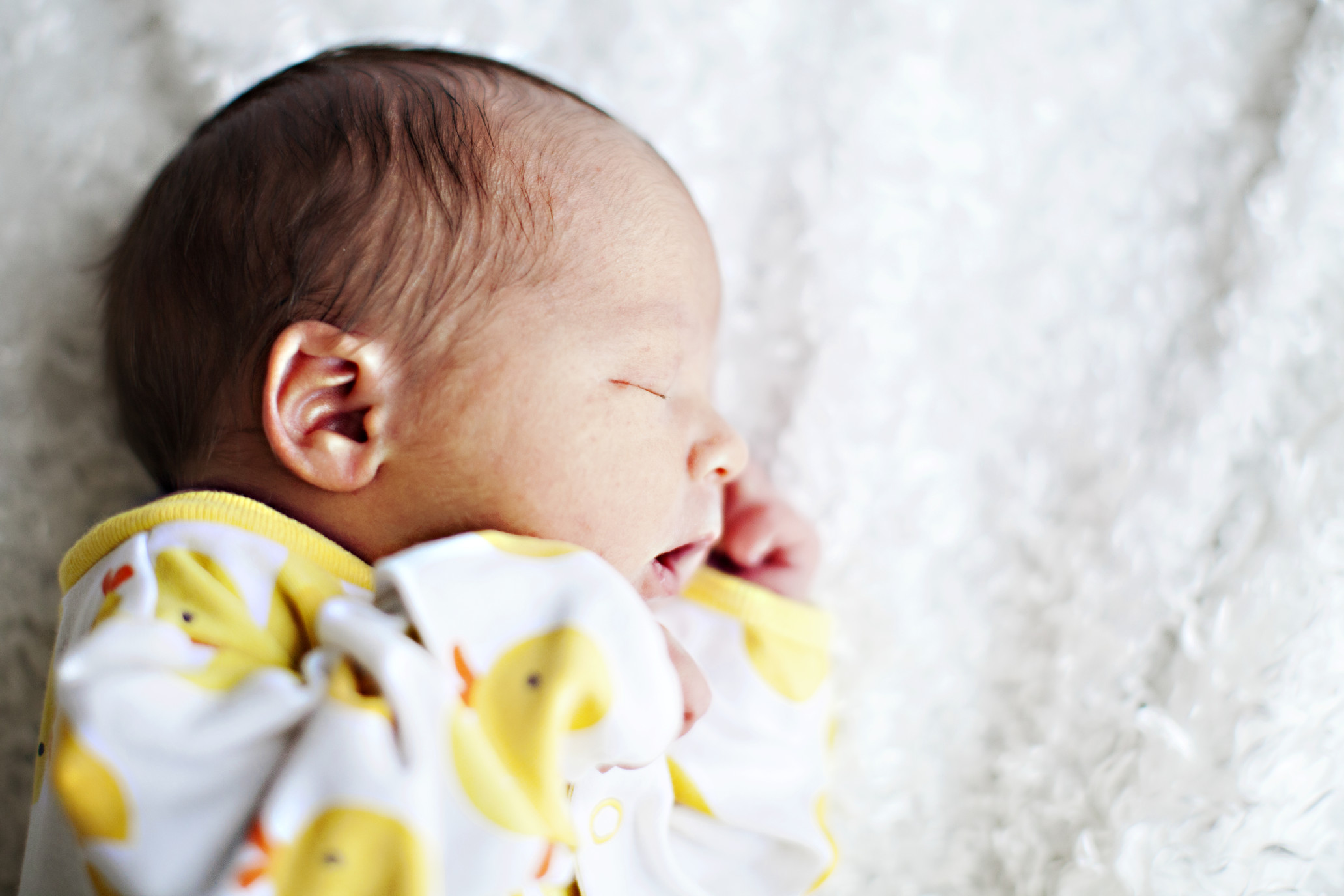 newborn-baby-in-yellow-pajamas-on-a-white-blanket-bathed-in-sunlight_t20_4EPZJl-1.jpg