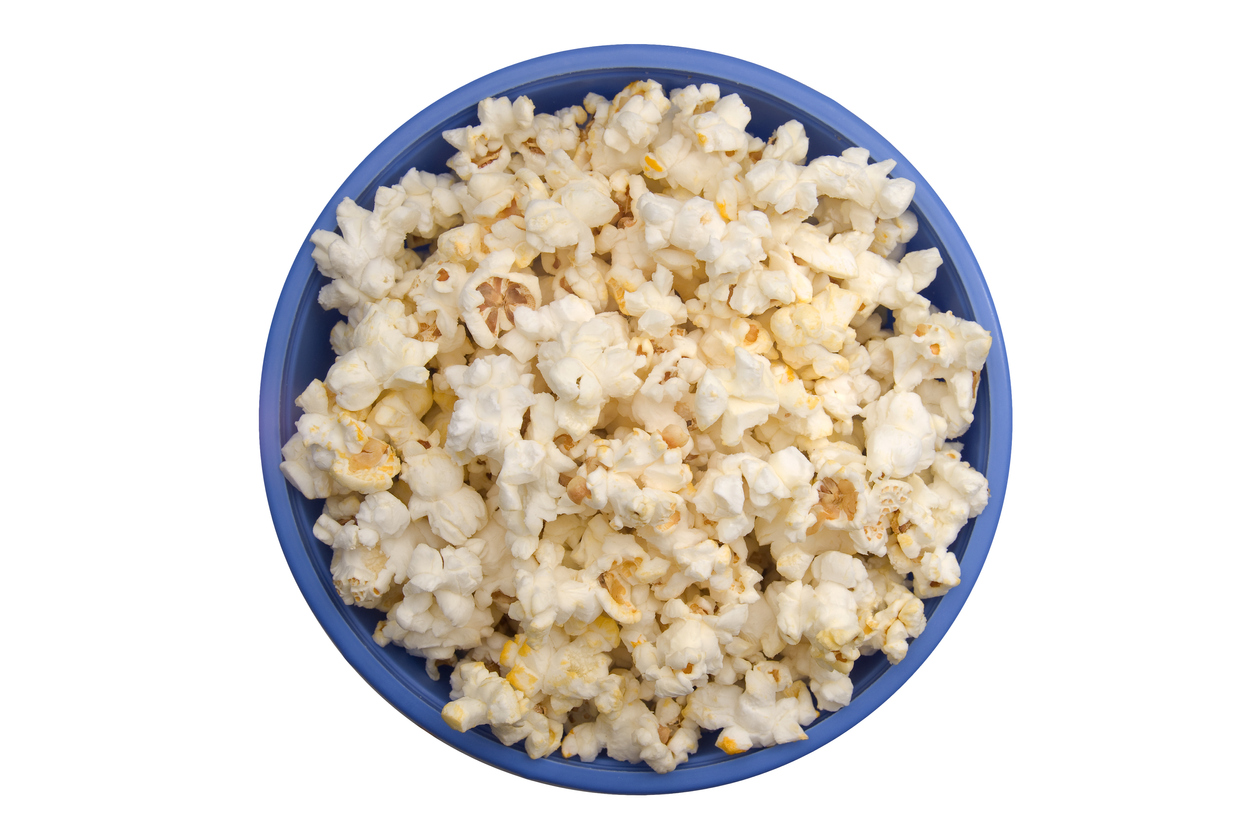 Aerial view of popped popcorn in a blue bowl on white table