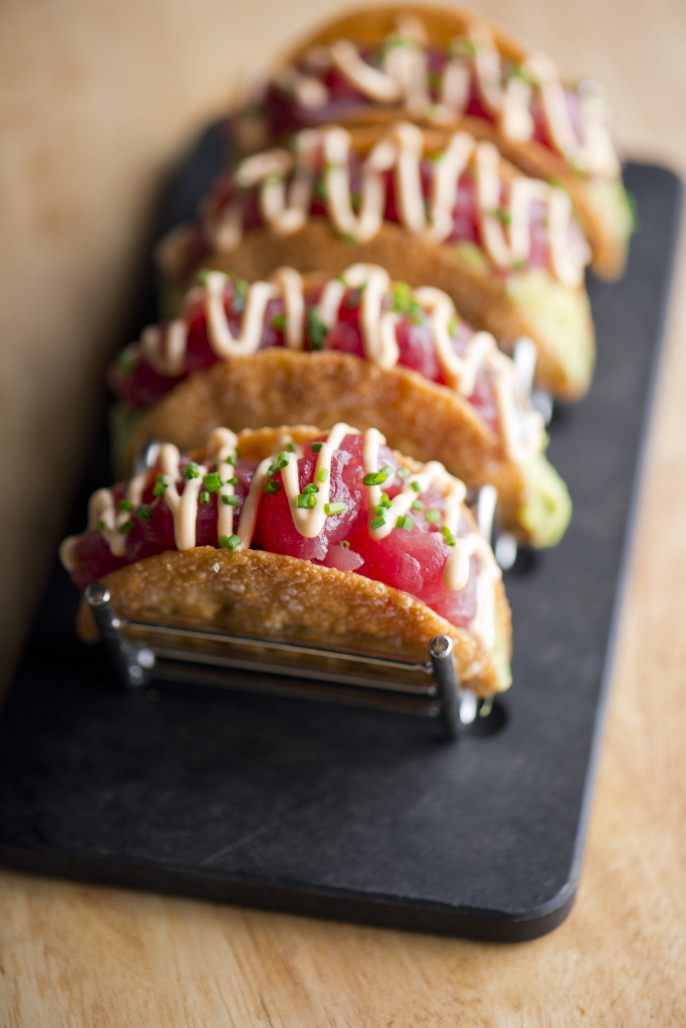 Ahi tuna tacos. Tuna tacos served in crispy shells with spicy wasabi sauce, avocado sliced and shisito leaves. Classic Japanese restaurant or American steakhouse appetizer favorite.