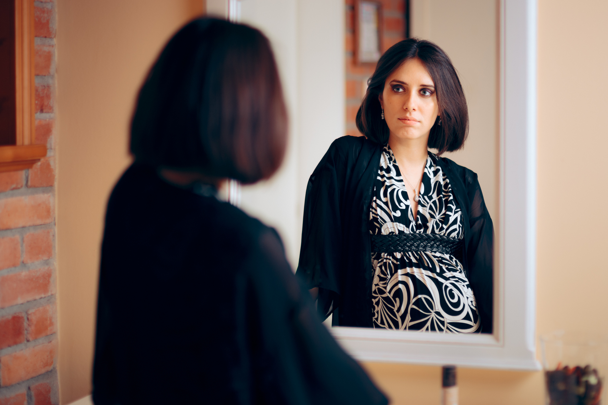 Introspective Pregnant Woman Analyzing Herself in a Mirror