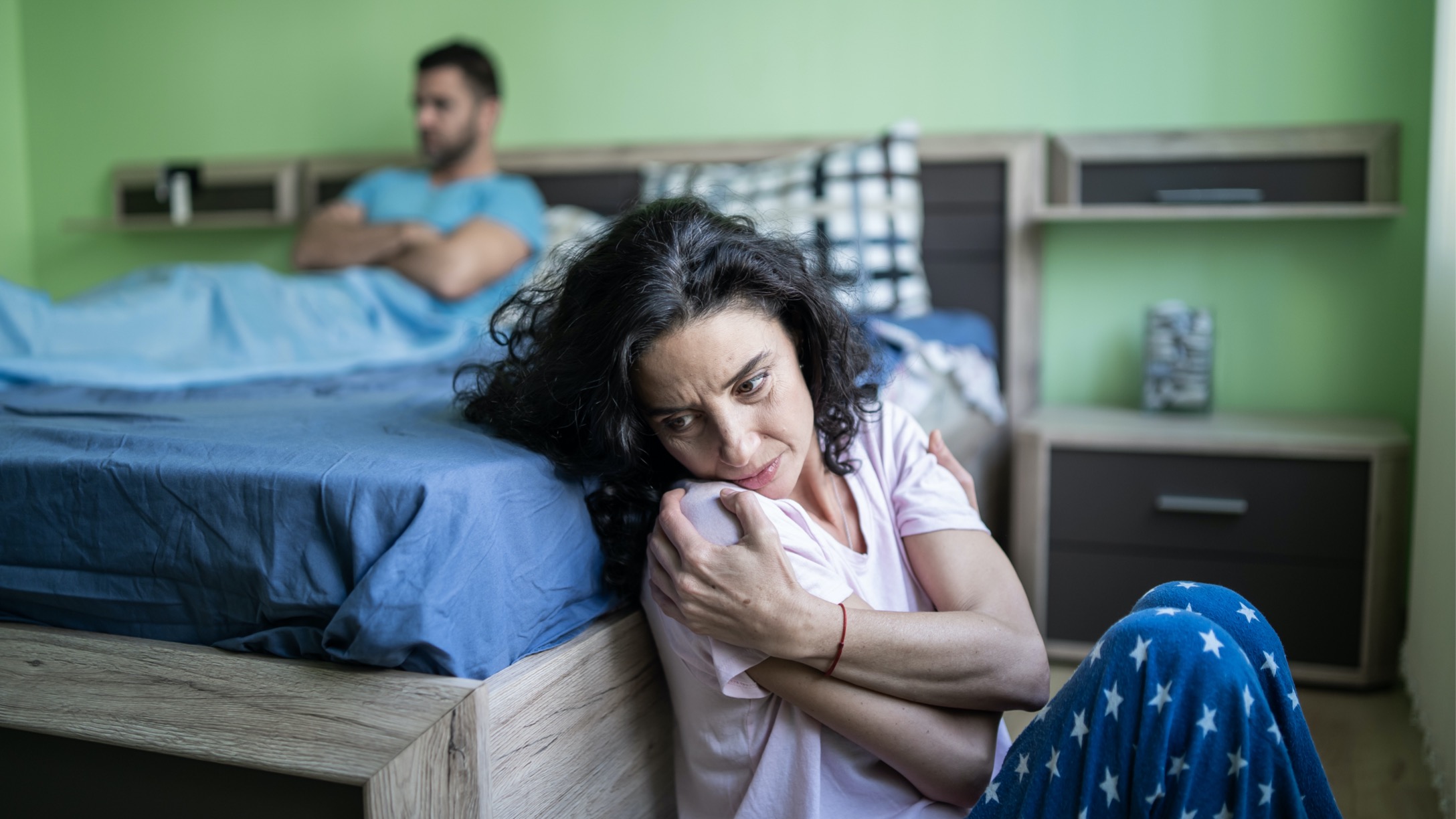 scared-woman-sitting-on-floor-next-to-bed-picture-id1219005931.jpg