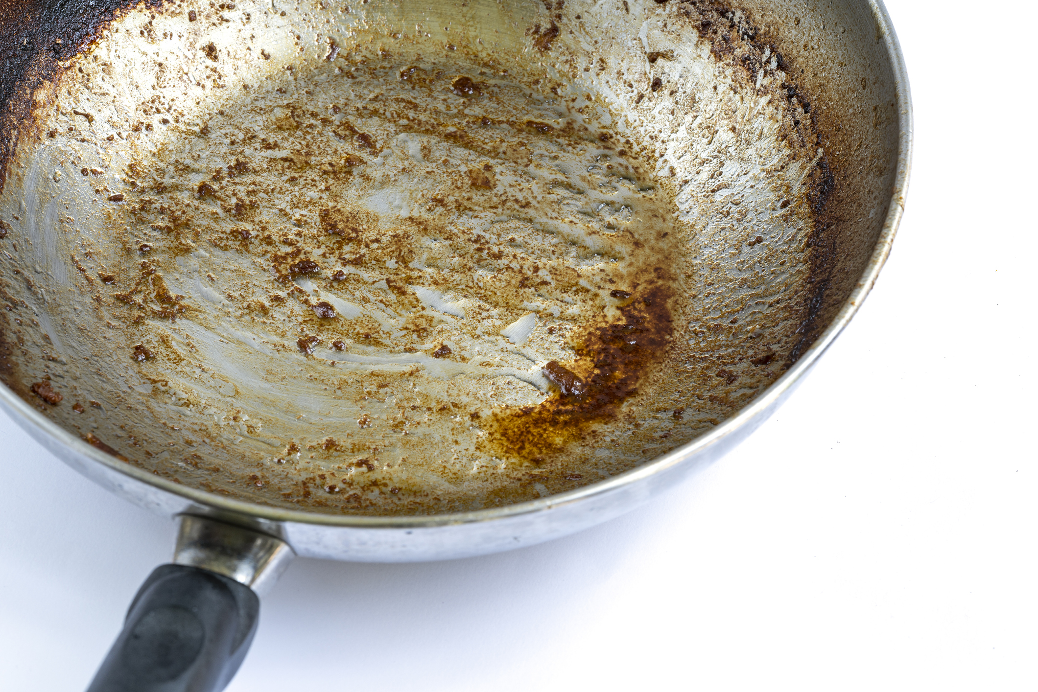 Close up used oil on iron frying pan with burning mark, oily stains after cooking. Ingrain burning on iron pan, black handle, big area of oily stains, burnt black blemish.