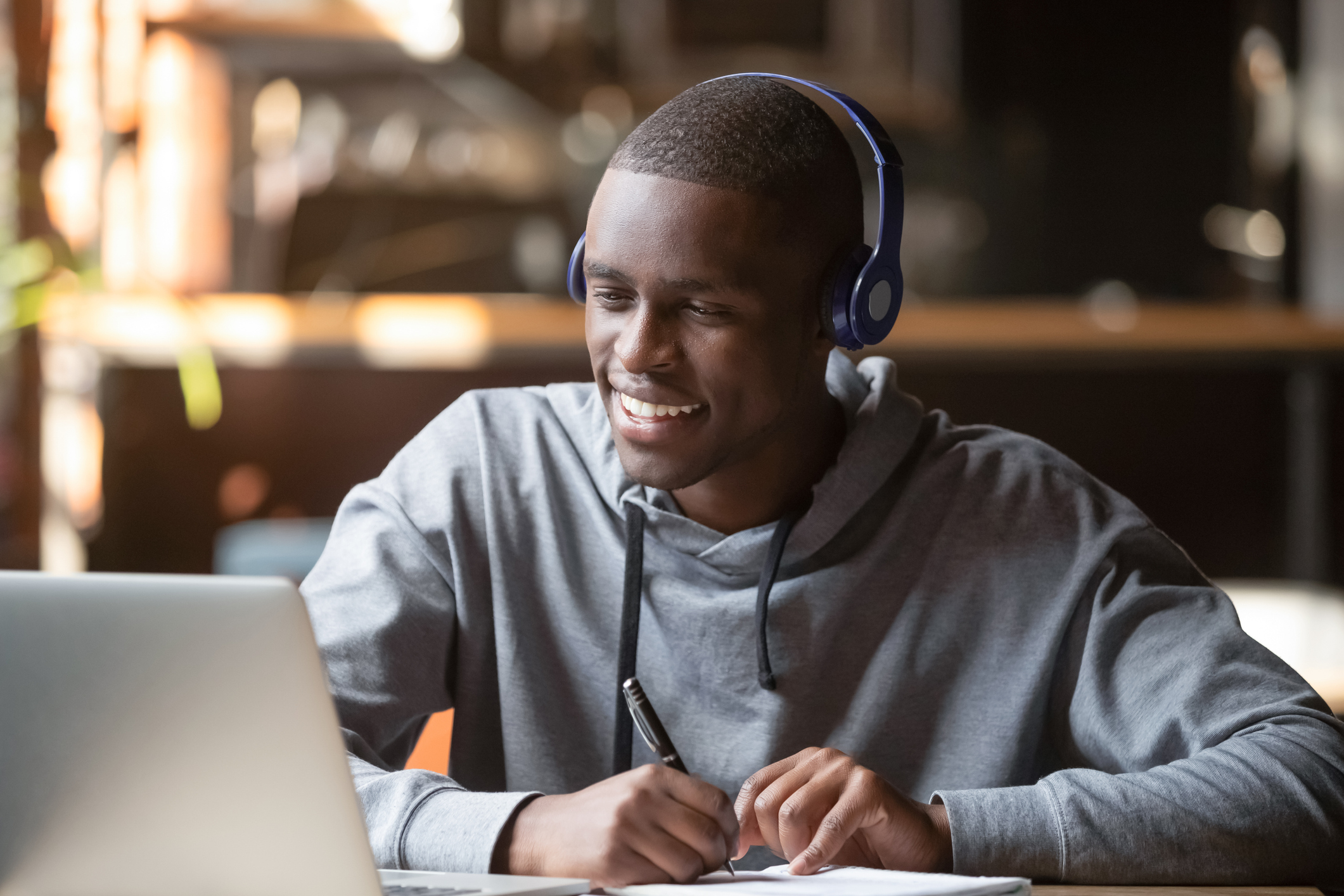 Smiling african young man student wearing headphones study online