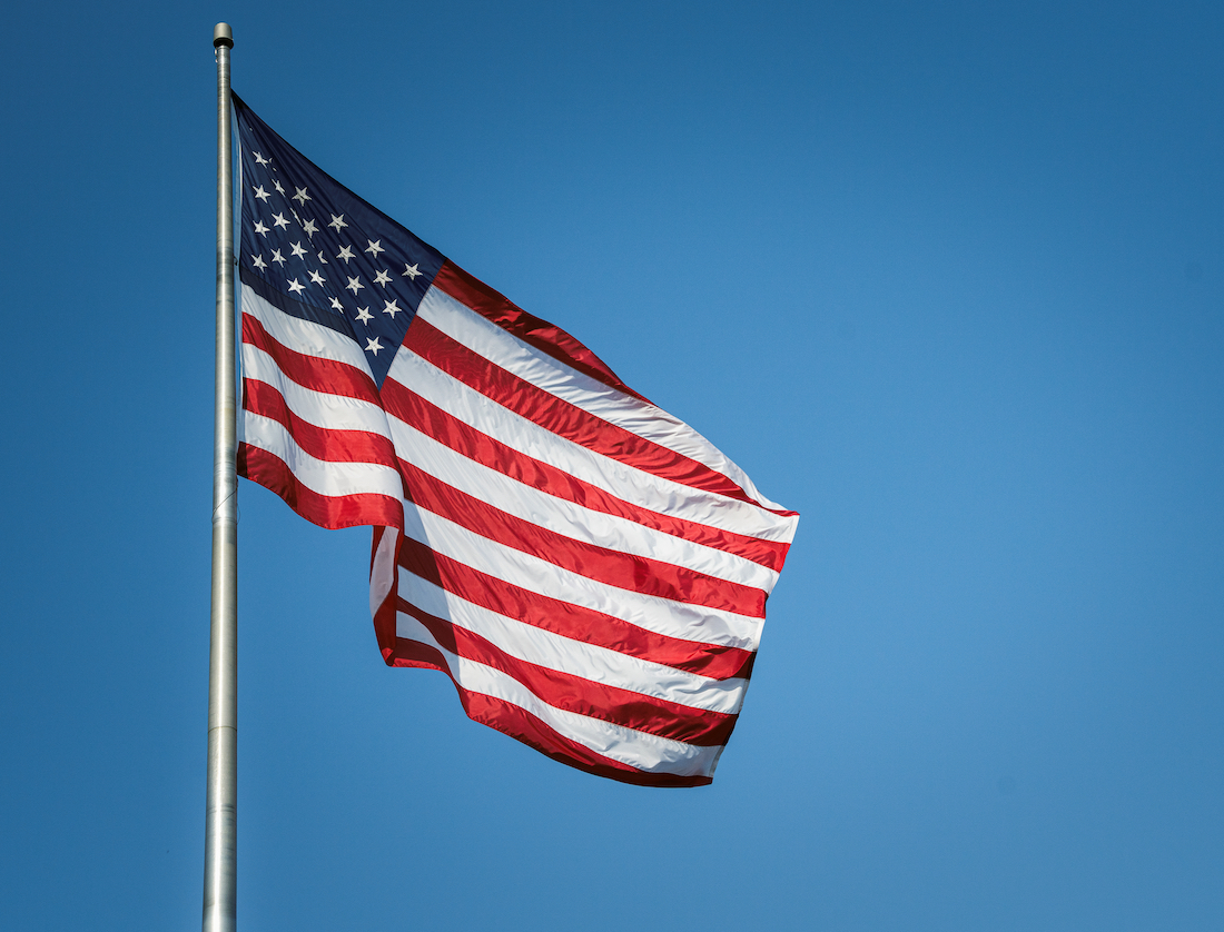 USA American flag flying against Blue Sky