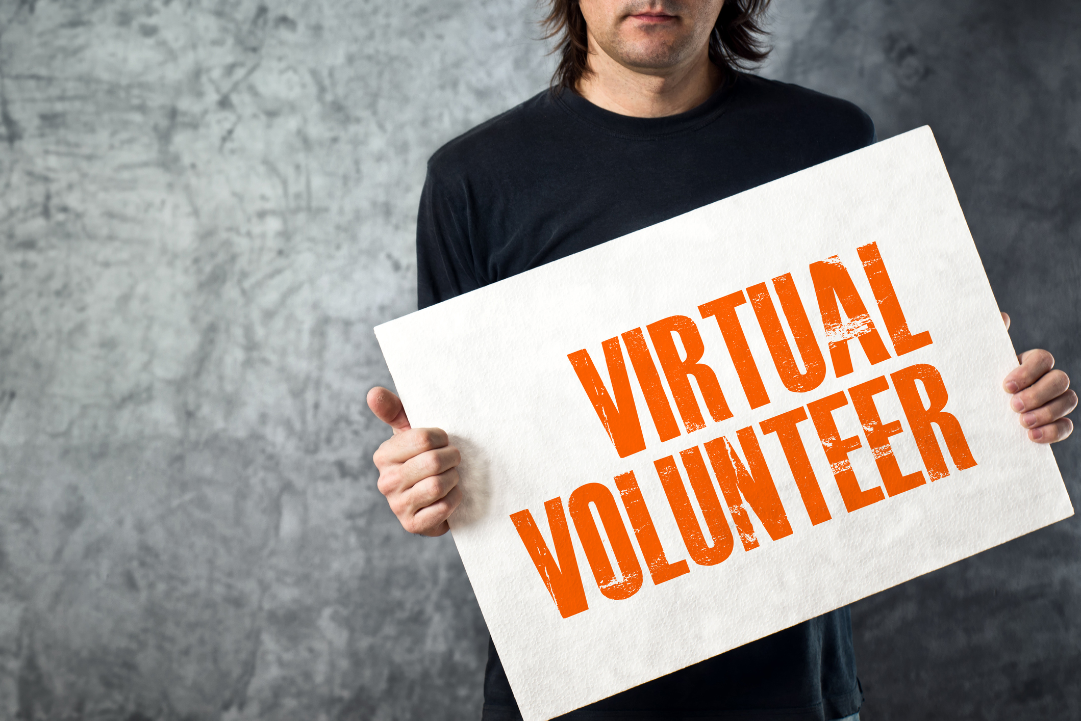 Man holding banner with VIRTUAL VOLUNTEER title