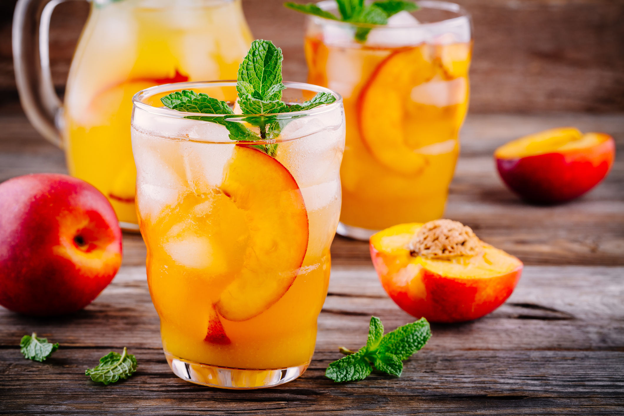 Summer cold drinks: homemade peach ice tea with ice cubes, and mint in glasses