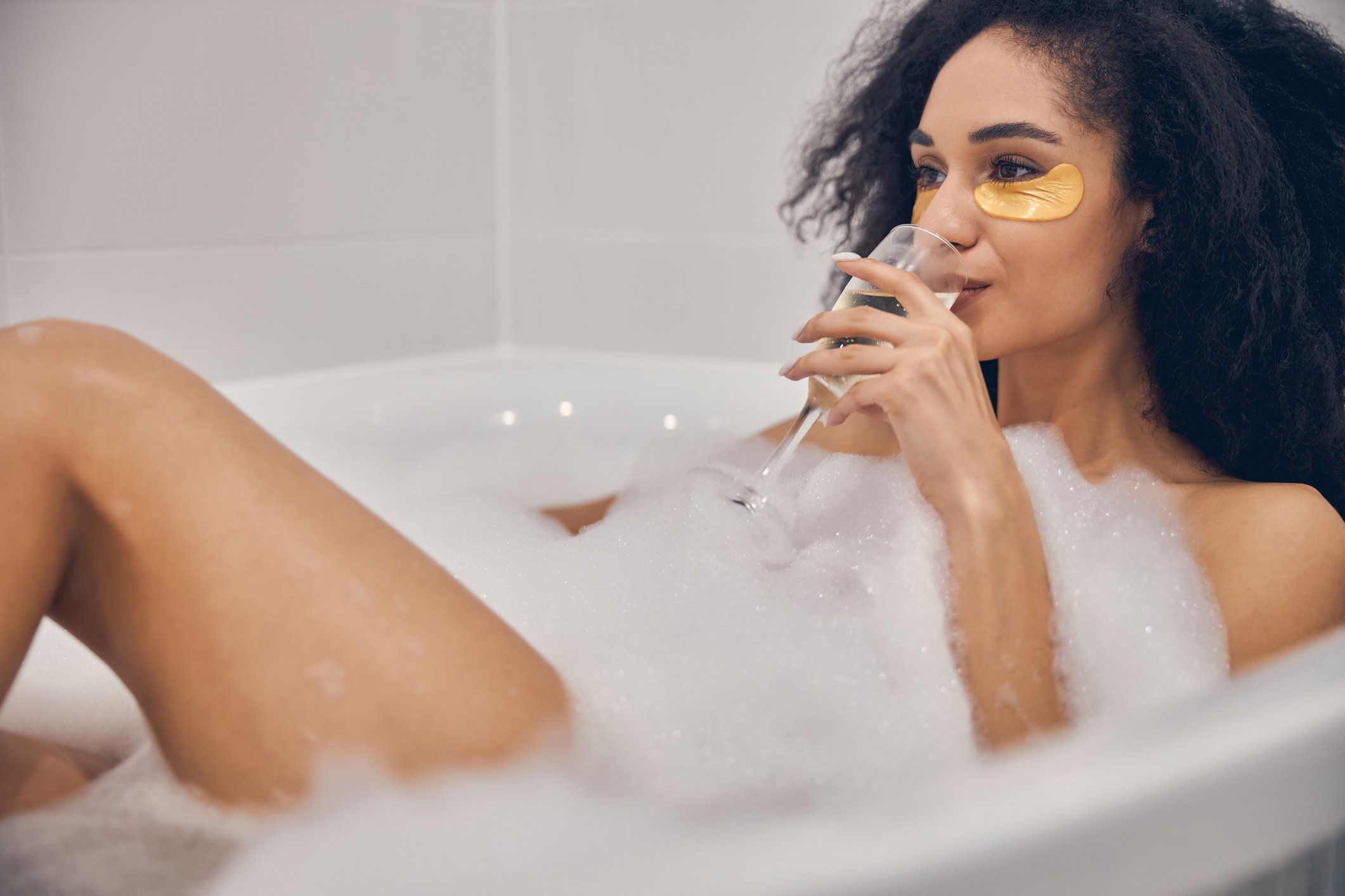 Female with a glass of beverage taking a bath