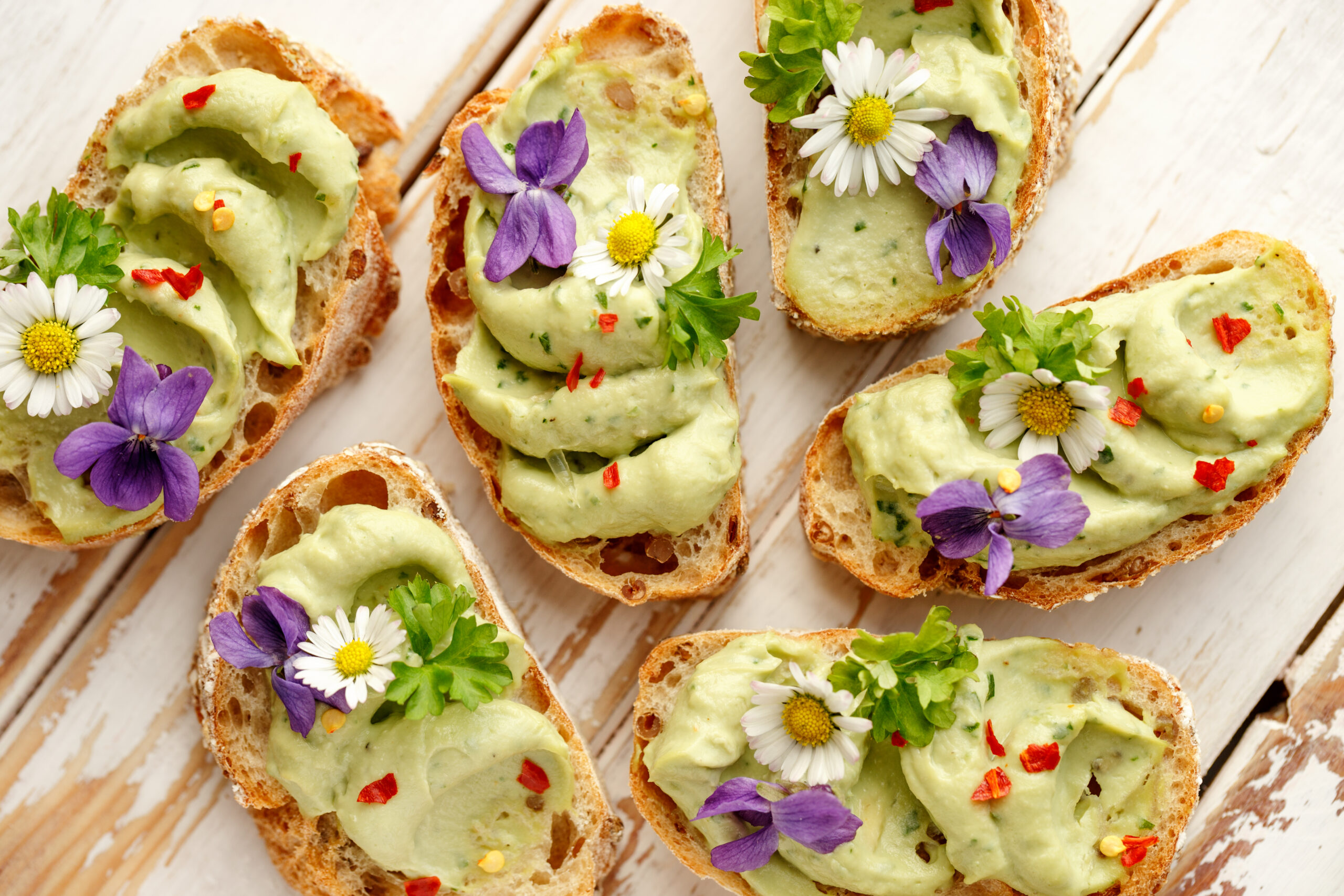 Canapes with avocado paste and edible flowers