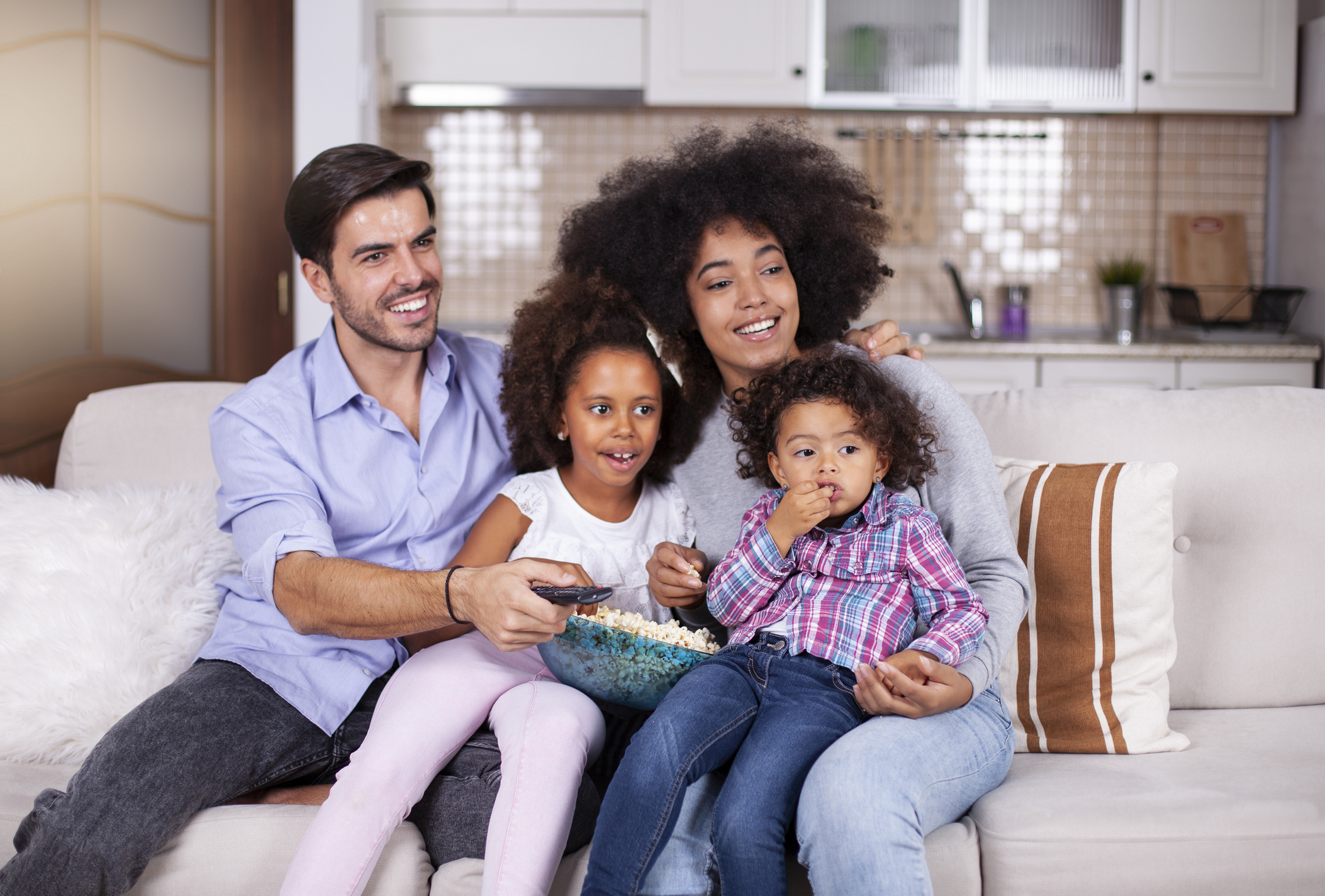 Cheerful African-American family having popcorn while watching television