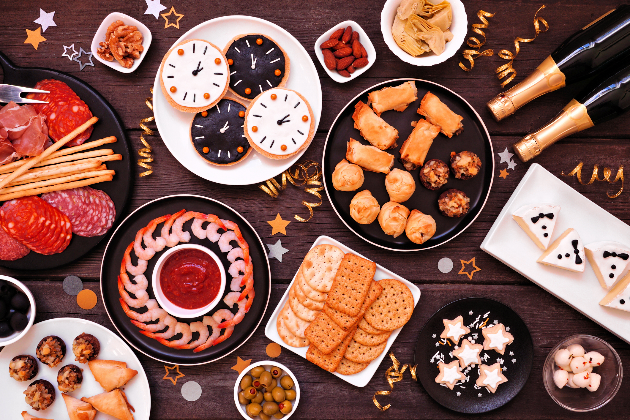 New Years Eve appetizer table scene. Overhead view on a dark wood background.