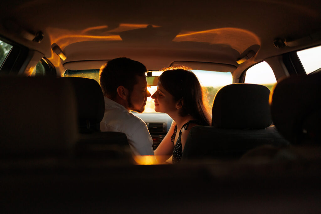 Couple in love kissing sitting in the car at sunset