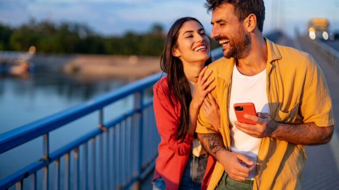 Couple walking across a bridge at sunset