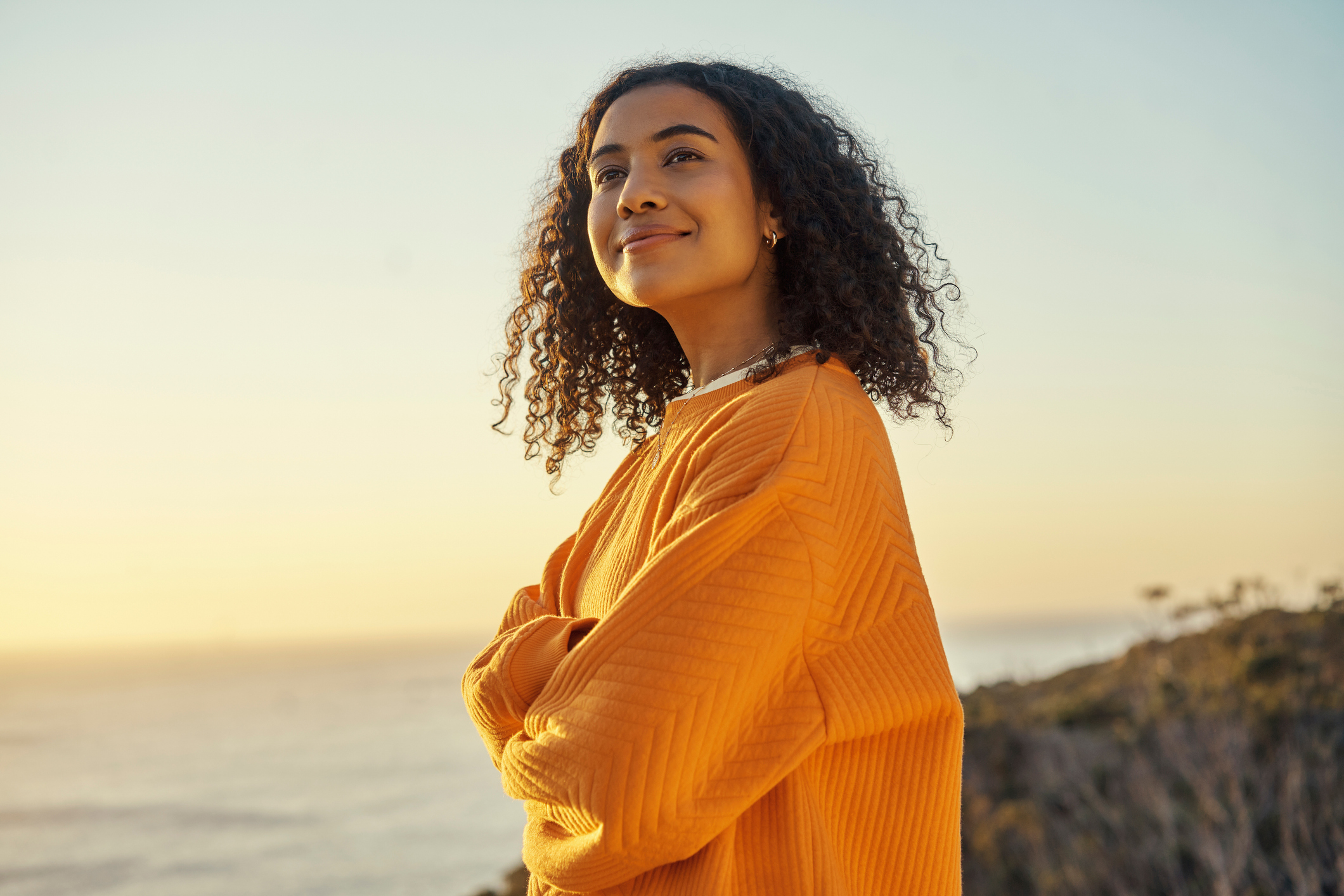 Happy, sunrise and woman in a beach portrait in nature thinking zen, peace and positively on a calm spring morning. Relax, smile and young girl on a weekend holiday vacation trip at the sea or ocean