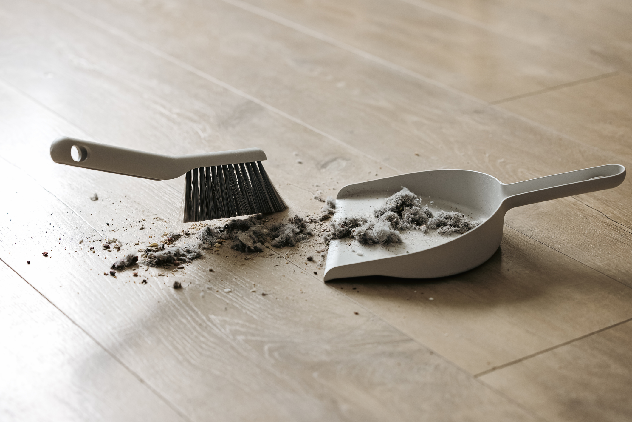 Sweeping dust with a broom on a dustpan