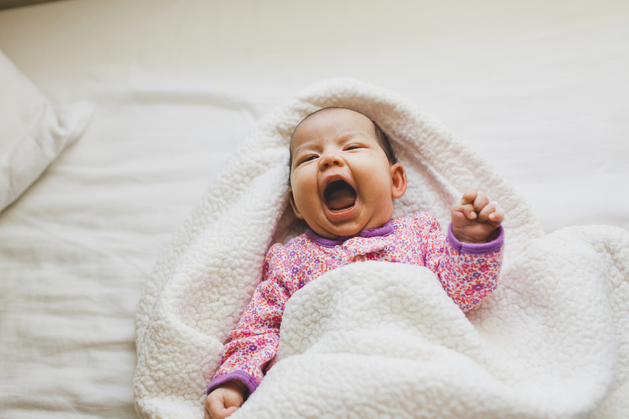 Baby girl laying on bed and laughing