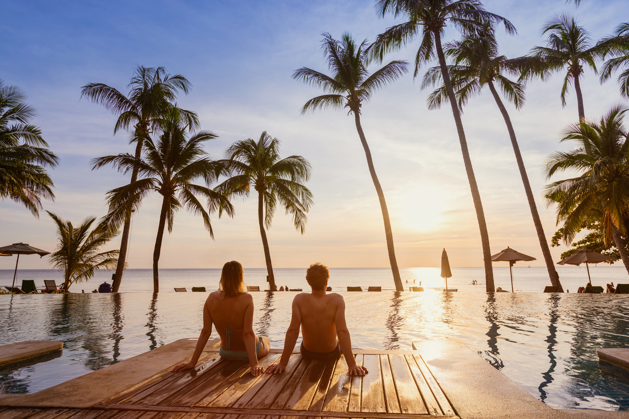 couple on the beach at sunset, honeymoon travel, man and woman sitting near swimming pool