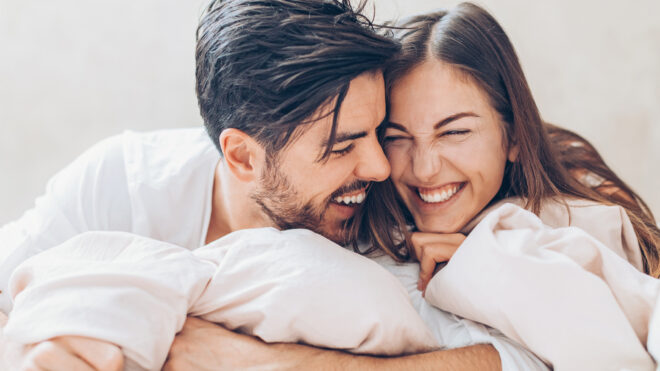 Two happy young people holding in bed