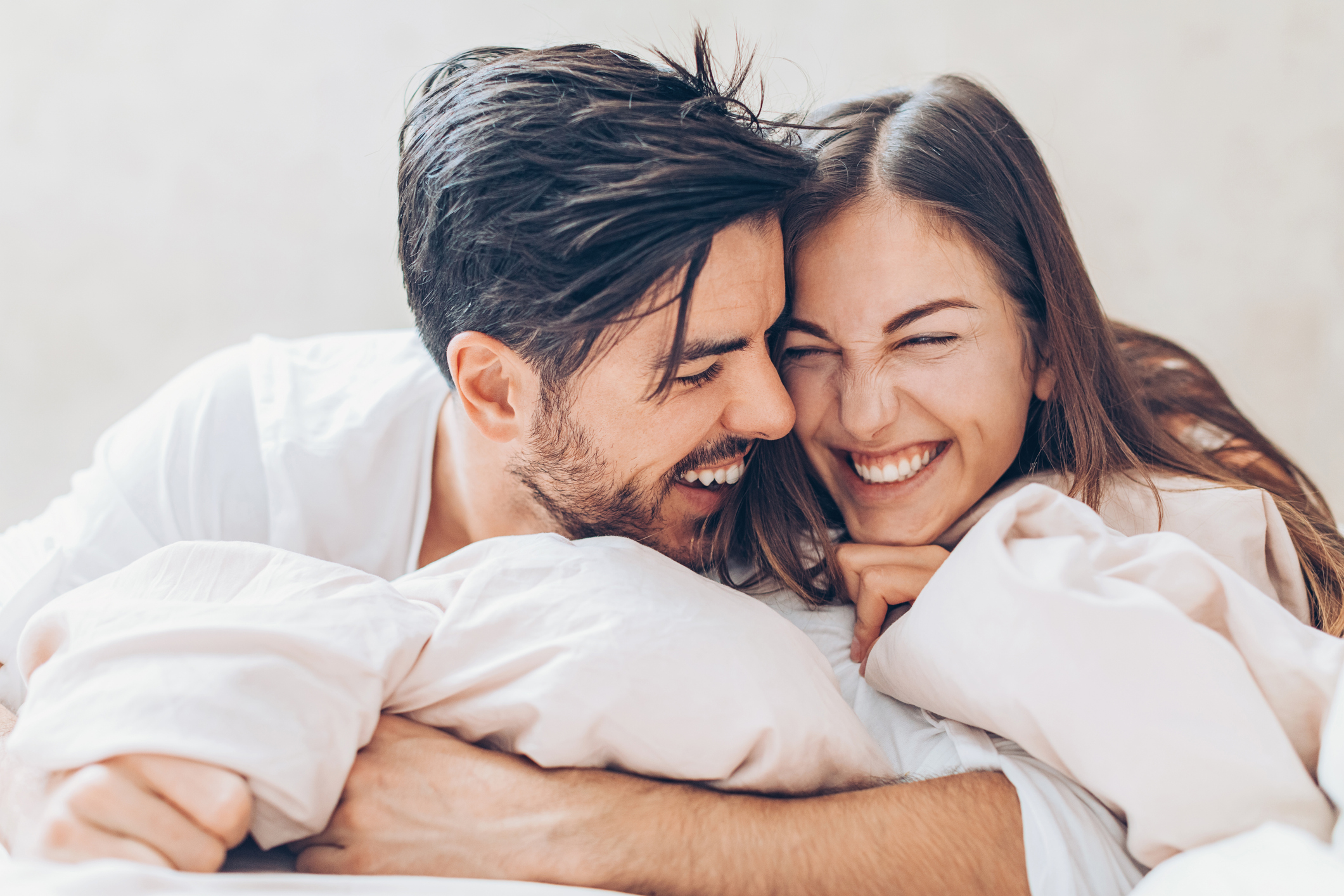 Two happy young people holding in bed