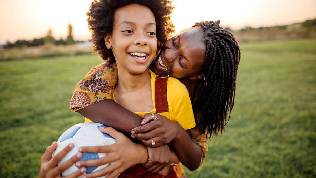 mom and child playing soccer together, she's hugging him