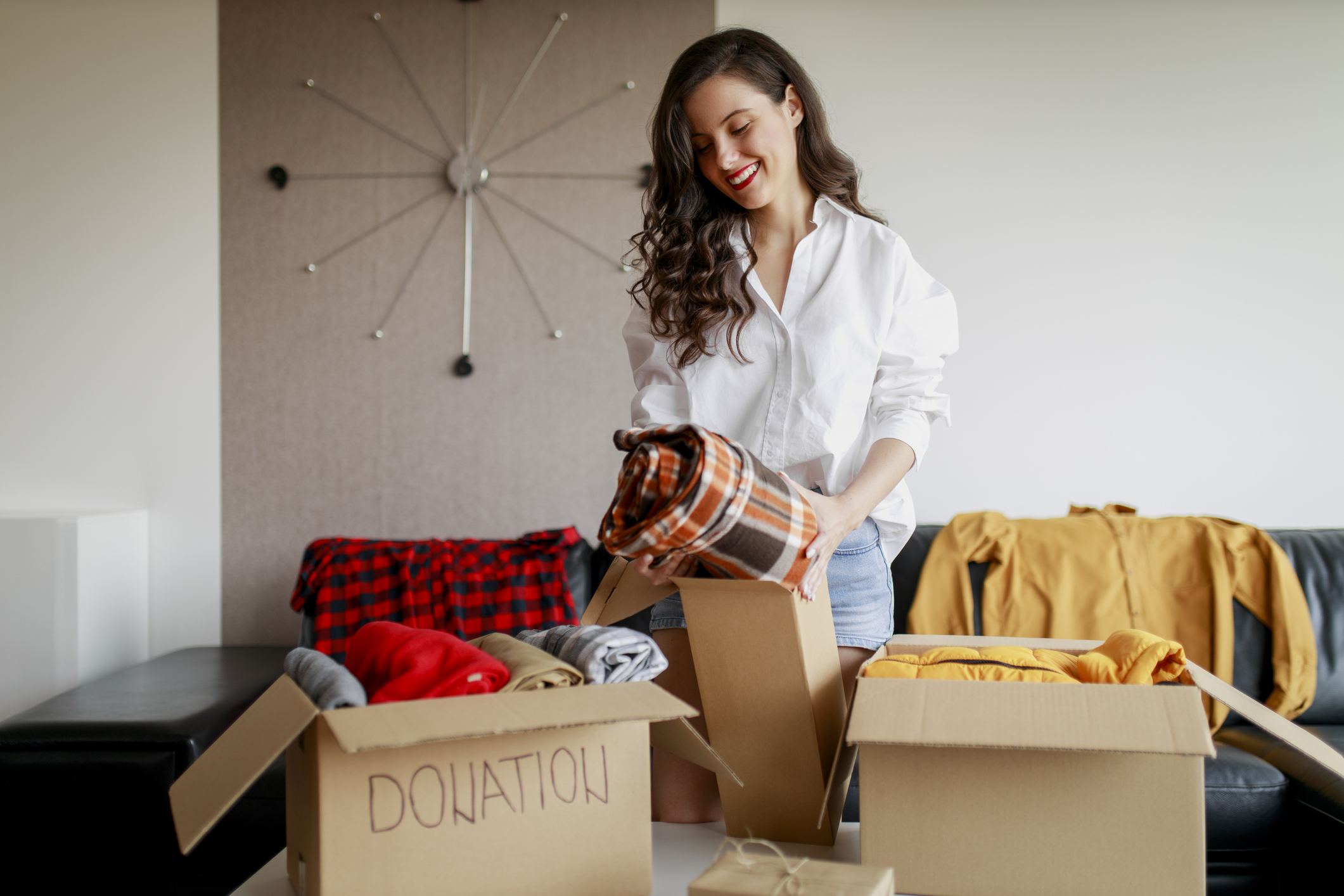 Woman sorting clothing and packing donation box