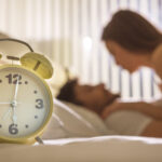 The clock on the background of the couple in the bed